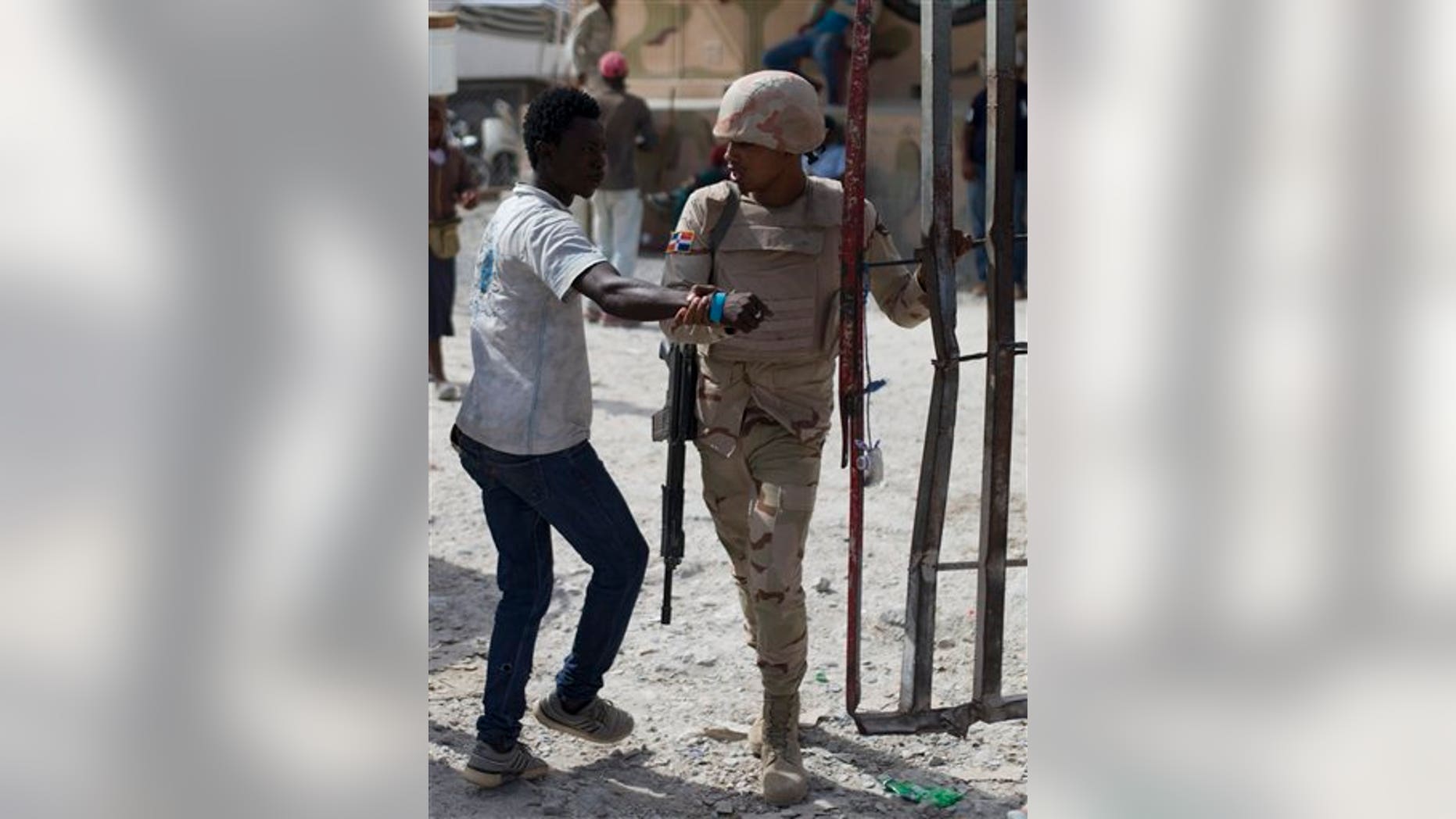 A Haitian man who tried to slip through is pulled back toward the Haitian side of the border by a Dominican soldier, in Malpasse, Haiti, Wednesday, June 17, 2015.
