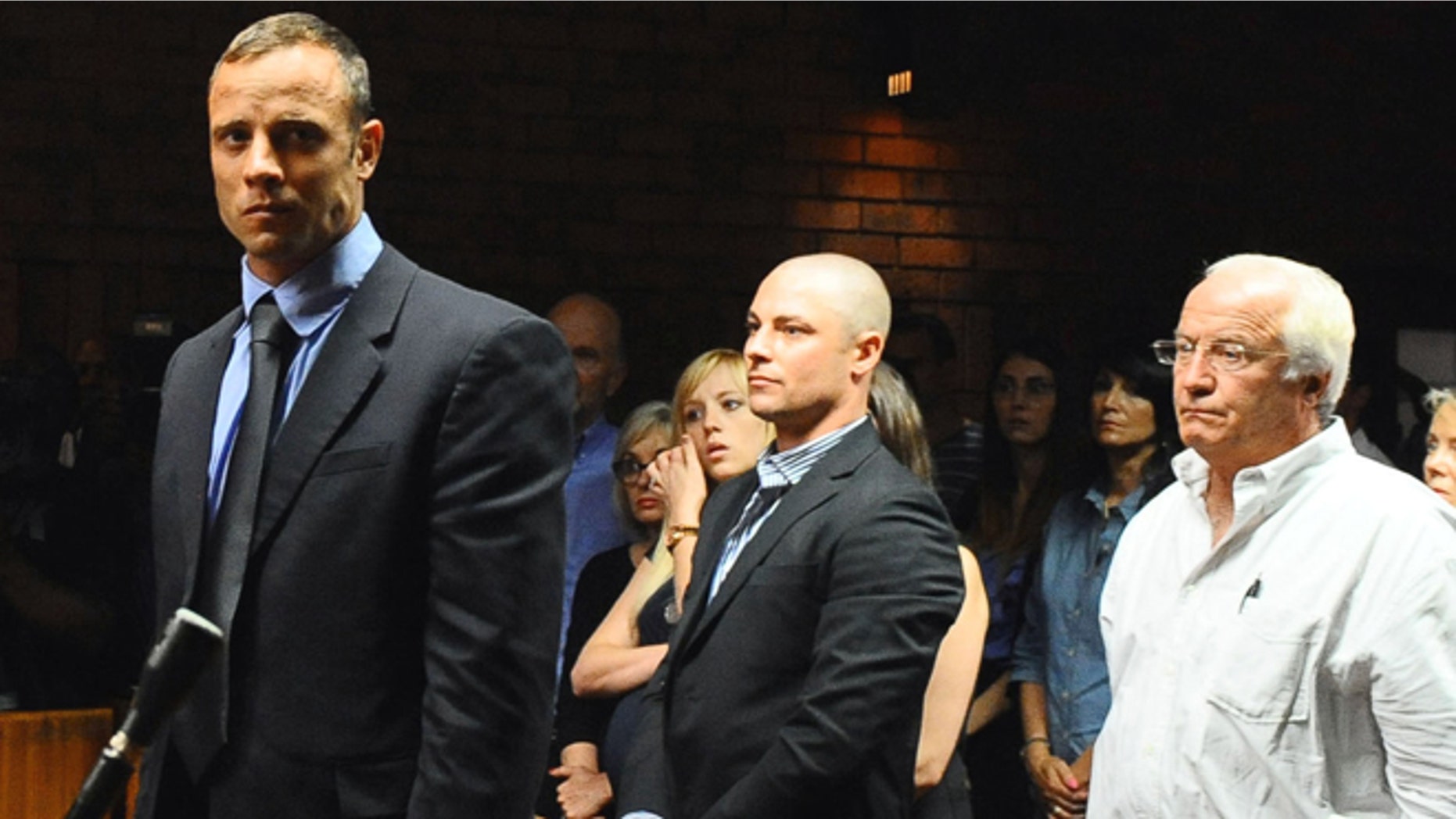 Feb. 19, 2013: Olympian Oscar Pistorius stands following his bail hearing, as his brother Carl, center, and father Henke look on, in Pretoria, South Africa.