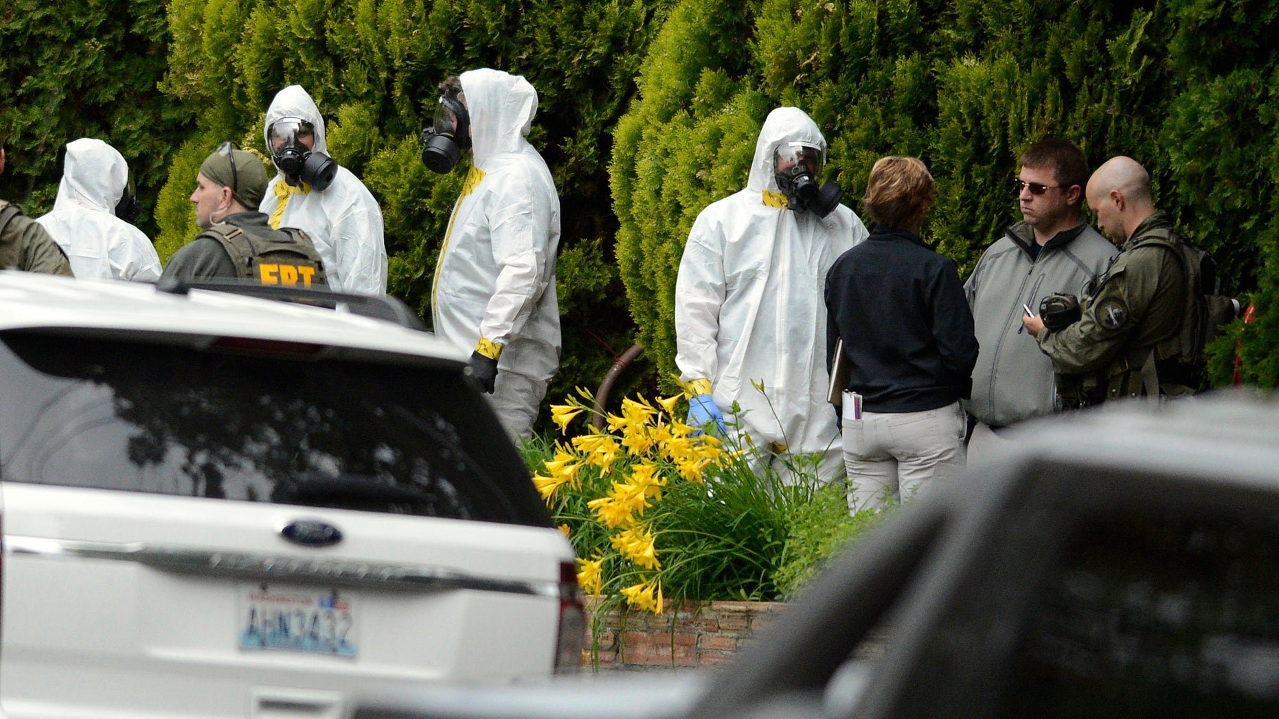 During the execution of a search warrant, members of the Joint Federal Haz-Mat Team, FBI, and local law enforcement gather in front of the Osmun Apartments near the intersection of First Avenue and Oak Street in Browne's Addition on Saturday, May 18, 2013 in Spokane, Wash. The search warrant is in connection with ricin-laced letters intercepted at a Post Office facility in Spokane earlier in the week. (AP Photo/TheSpokesman-Review, Colin Mulvany) COEUR D'ALENE PRESS OUT