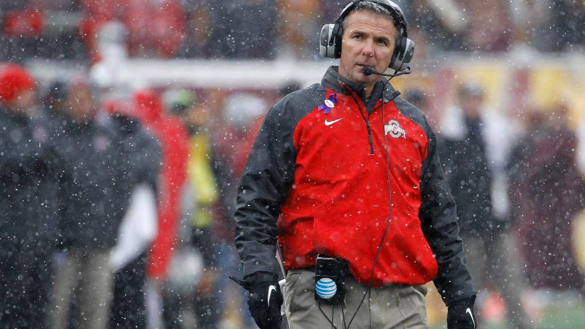 Ohio State head coach Urban Meyer walks out to his players in a timeout as snow falls during the fourth quarter of an NCAA college football game against Minnesota in Minneapolis Saturday, Nov. 15, 2014. Ohio State won 31-24. (AP Photo/Ann Heisenfelt)