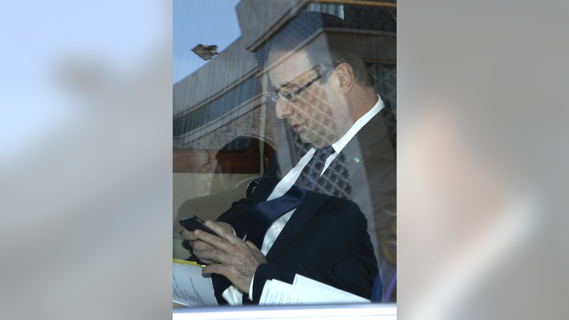 French President Francois Hollande looks at his mobile phone as he sits in a limousine after visiting the Hassan II mosque in Casablanca, Morocco Thursday, April 4, 2013. French President Hollande is on the second-day of a state visit to Morocco. (AP Photo/Youssef Boudlal/Pool)