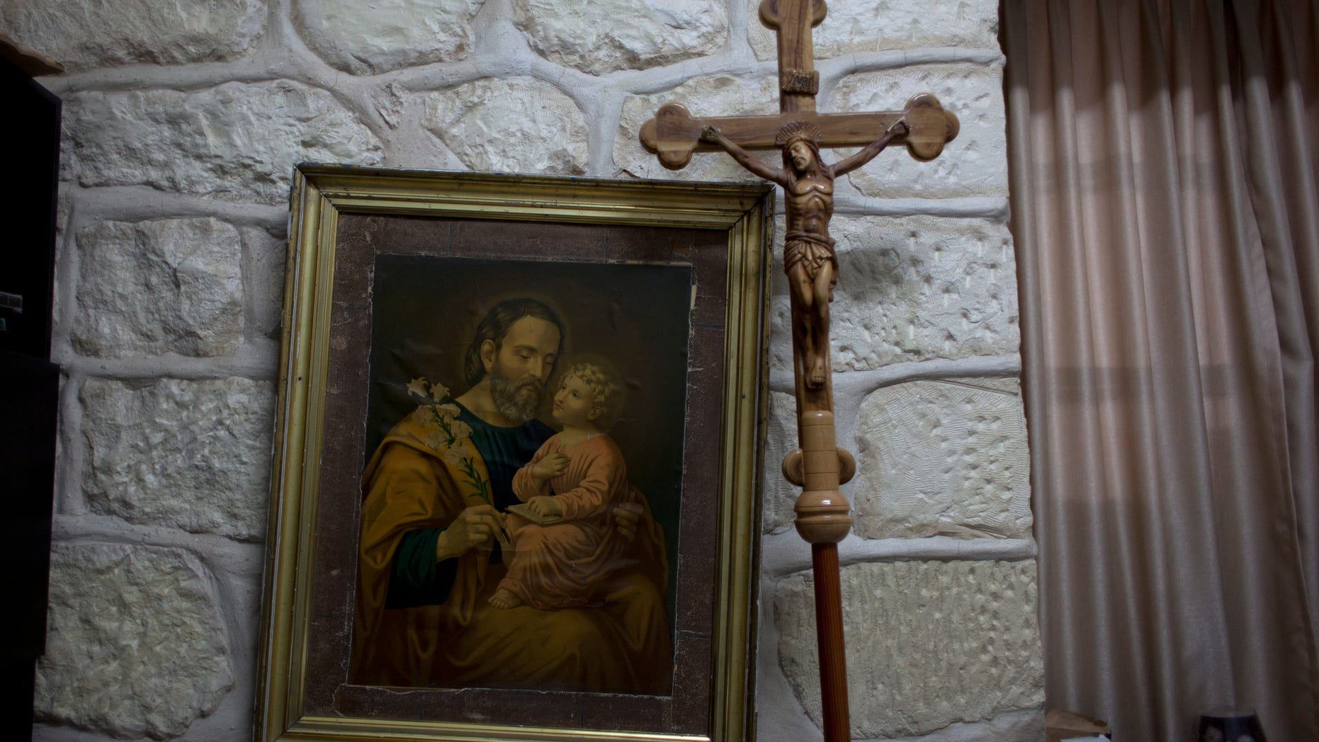 In this photo taken Sunday, May 18, 2014, a wooden cross and a painting is seen at the office of Father Ibrahim Shomali, the parish priest of Beit Jala and leads meditating efforts between local Christians and Palestinian Christian emigre families who abandoned their homes, in order to keep Christian properties among Christians, at the Annunciation Latin Church, in the West Bank town of Beit Jala. Pope Francis will be arriving this weekend to the land where Christianity was born, and where Christians are disappearing. The Christian community in the Holy Land is one of the oldest in the world. But it has dwindled to around 2 percent of the population today, as economic hardship, violence and the bitter realities of the Israeli-Palestinian conflict have sent them searching for better opportunities overseas. (AP Photo/Nasser Nasser)