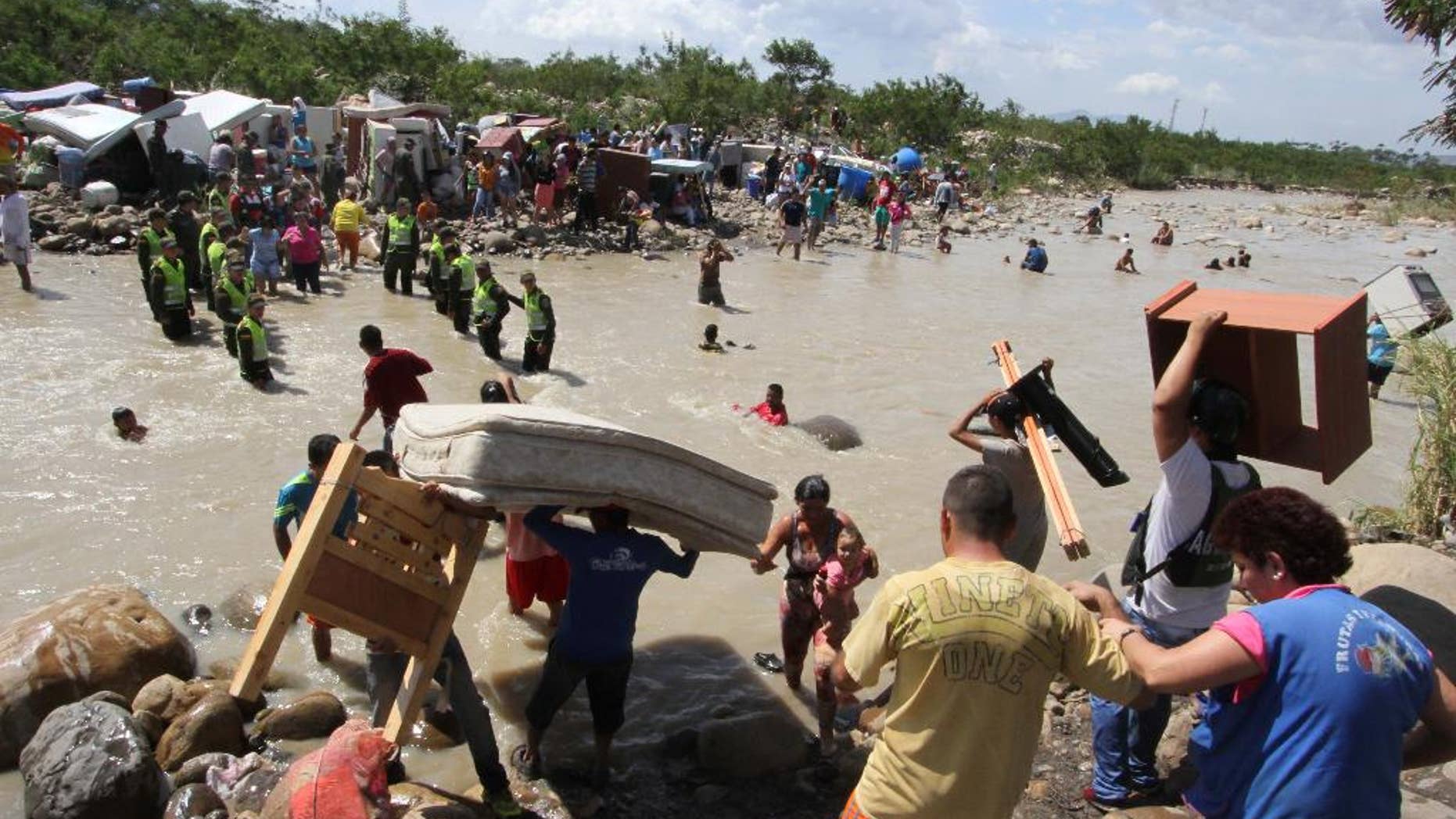 In this Tuesday, Aug. 25, 2015 photo, people carry their household belongings across the Tachira River from Venezuela, foreground, to Colombia, near San Antonio del Tachira, Venezuela, during a mass exodus of Colombians living on the Venezuelan side of the border. Venezuelan President Nicolas Maduro vowed to extend a crackdown on illegal migrants from neighboring Colombia he blames for rampant crime and widespread shortages, while authorities across the border struggled to attend to droves of returning deportees. (AP Photo/Eliecer Mantilla)