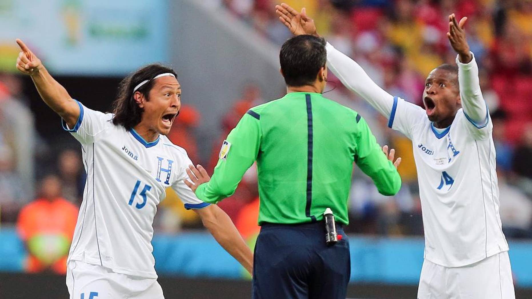 10ThingstoSeeSports - Honduras players Roger Espinoza, left, and Luis Garrido complain to referee Sandro Ricci from Brazil after he awarded a goal to France using goal line technology during the group E World Cup soccer match between France and Honduras at the Estadio Beira-Rio in Porto Alegre, Brazil, Sunday, June 15, 2014. (AP Photo/David Vincent, File)