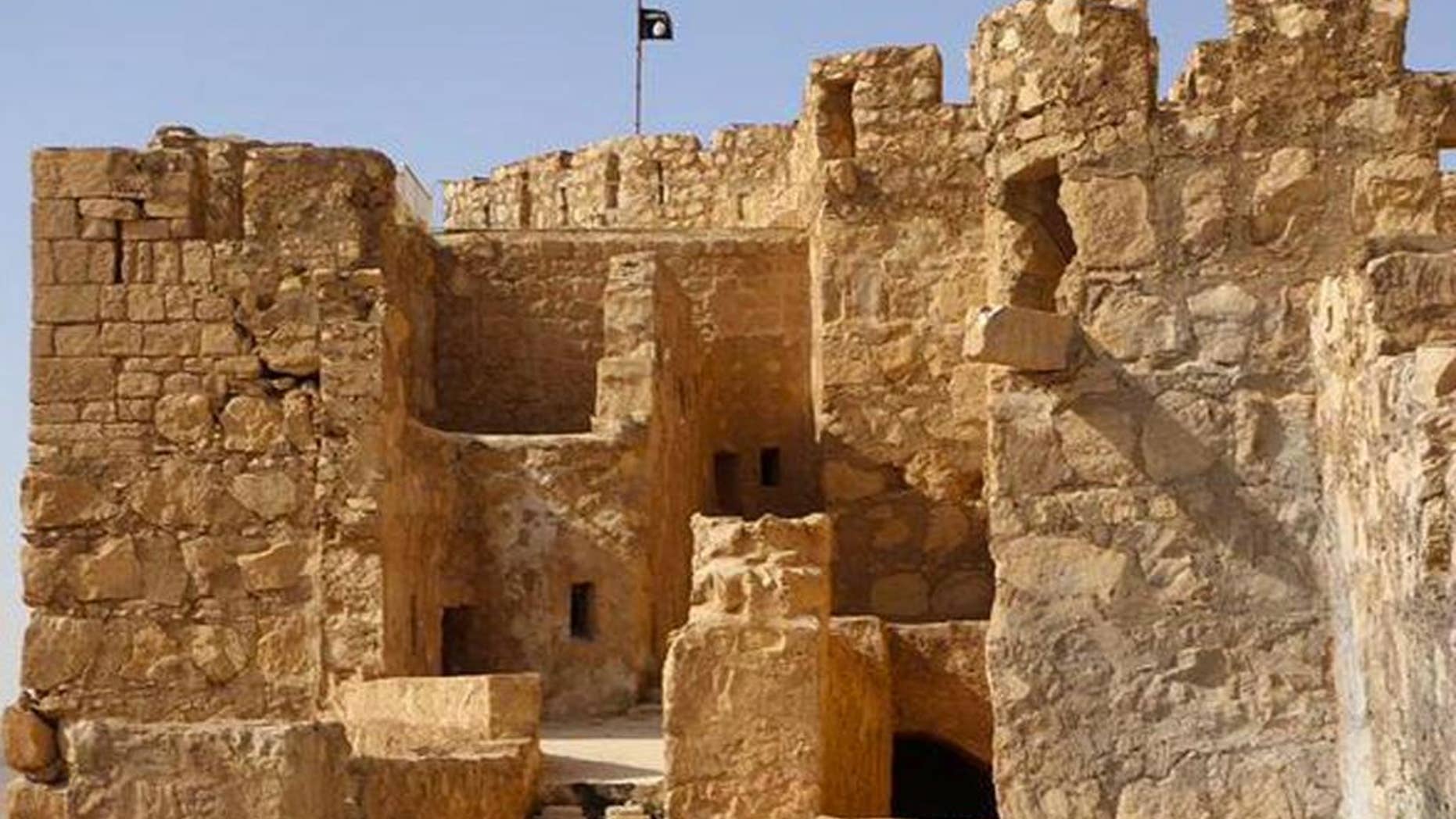 In this picture released on Friday, May 22, 2015 by the website of Islamic State militants, shows the Islamic State militants flag, top center, raised on the to top of Palmyra castle, in the Syrian town of Palmyra, Syria. A Syrian official in charge of antiquities says Islamic State fighters have broken into the museum of the ancient town of Palmyra which they have captured days earlier, but have not harmed its contents. (The website of Islamic State militants via AP)