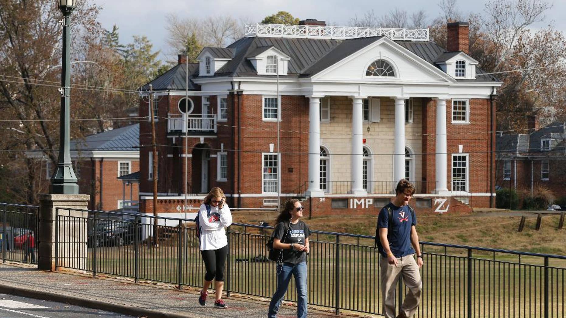 FILE - In this Monday, Nov. 24, 2014, file photo, University of Virginia students walk to campus past the Phi Kappa Psi fraternity house at the University of Virginia in Charlottesville, Va. Rolling Stone is casting doubt on the account it published of a young woman who says she was gang-raped at a Phi Kappa Psi fraternity party at the school, saying there now appear to be discrepancies in the student's account. (AP Photo/Steve Helber, File)