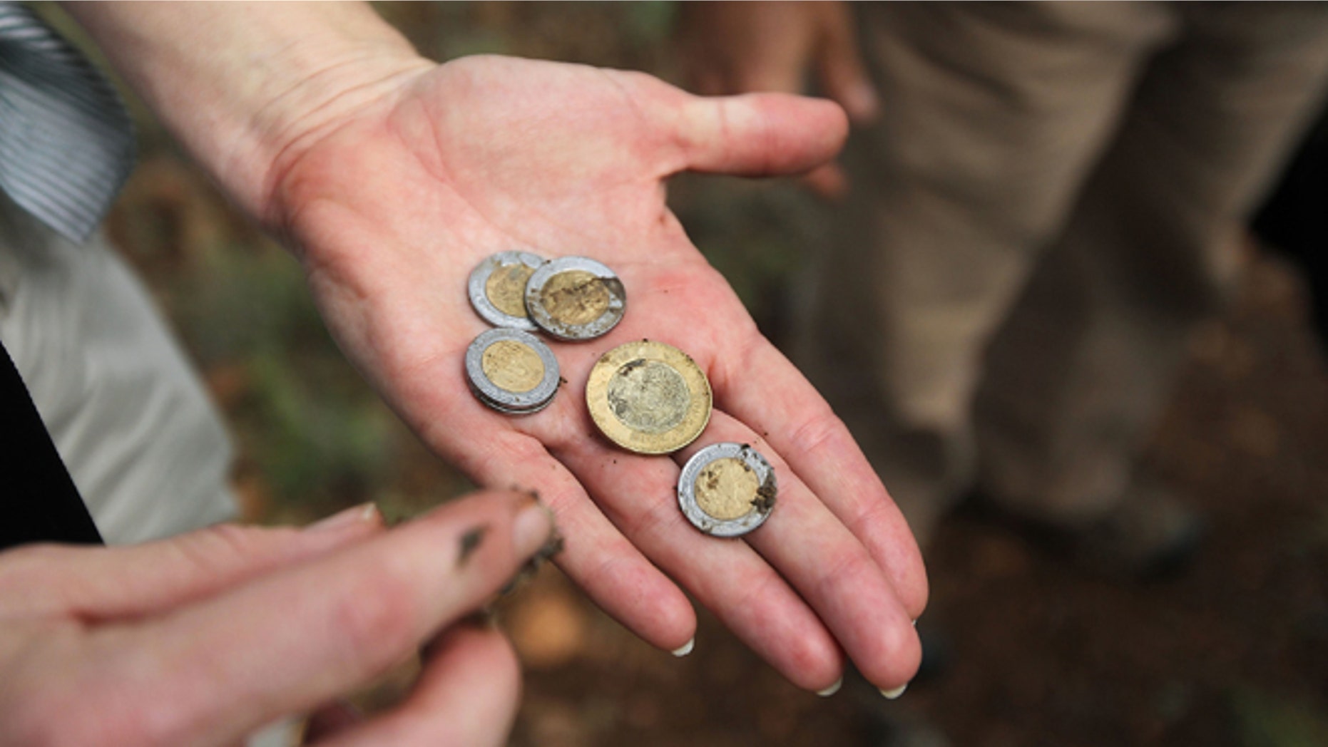 GREEN VALLEY, AZ - JULY 31: Volunteer Rebecca Fowler displays Mexican pesos found in a backpack discarded by immigrants crossing into Arizona from Mexico along a backcountry trail on July 31, 2010 near Green Valley, Arizona. She was on a patrol for the non-profit group Samaritans, which delivers water to points near the U.S. Mexico border for immigrants crossing illegally into Arizona. Samaritans volunteers also provide medical assistance for distressed migrants, who often suffer from severe dehydration while crossing the desert. Immigrant aid groups and law enforcement alike say that the number of immigrants crossing illegally into Arizona from Mexico has slowed dramatically in 2010, with jobs scarce due to the U.S. recession and widespread fear in the Latino community associated with Arizona's new immigration enforcement law SB 1070. (Photo by John Moore/Getty Images) *** Local Caption *** Rebecca Fowler