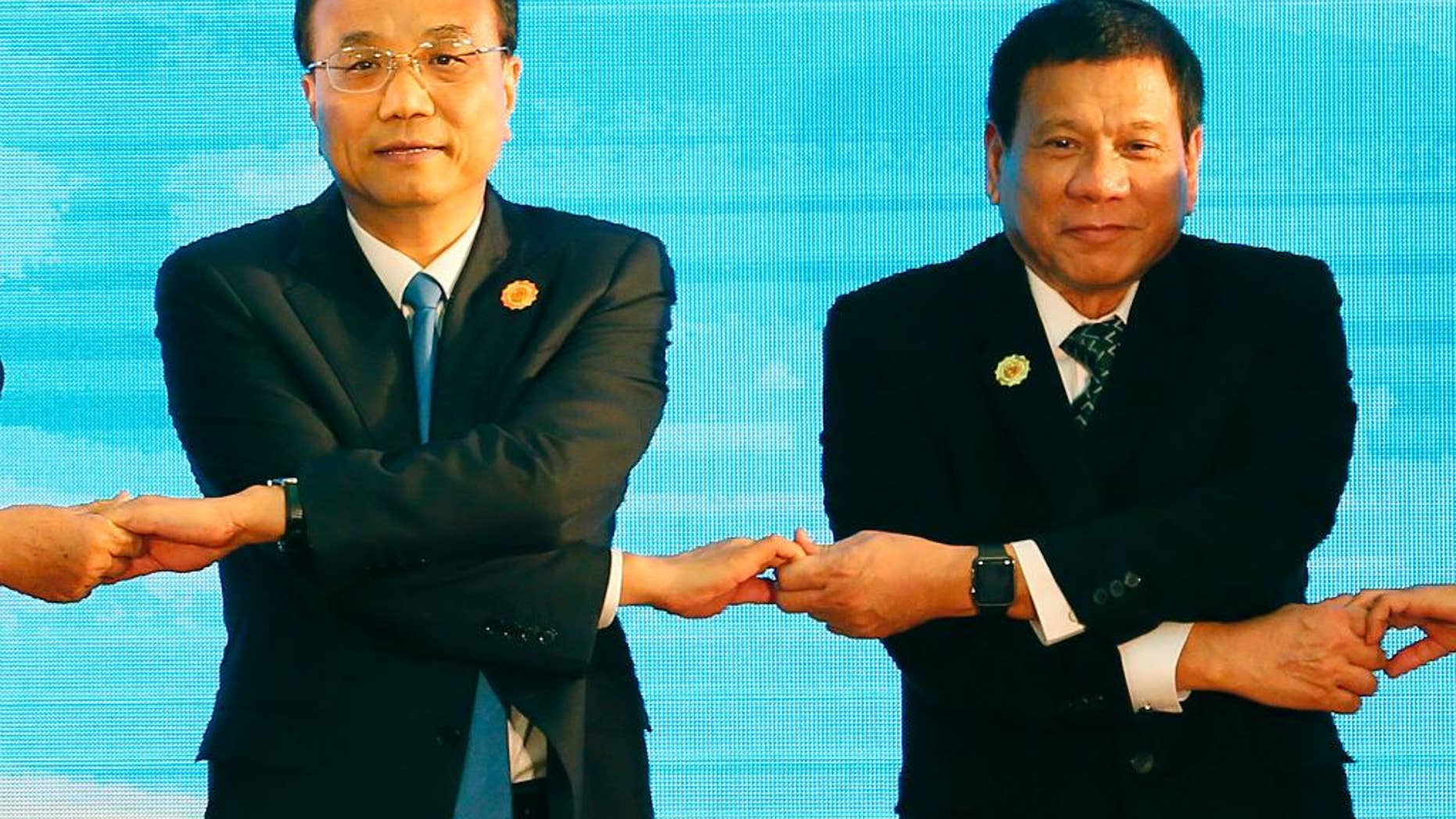 FILE - In this Sept. 7, 2016 file photo, Chinese Prime Minister Li Keqiang, left, and Philippine President Rodrigo Duterte link arms during the ASEAN Plus Three summit in the ongoing 28th and 29th ASEAN Summits and other related summits at the National Convention Center in Vientiane, Laos. After lashing out at longtime ally America, the new Philippine president is making a state visit to China in a charm offensive that will help define how far he wants to shift allegiance from treaty ally the U.S. to an Asian superpower locked in a territorial standoff with his small, impoverished country. (AP Photo/Bullit Marquez, File)