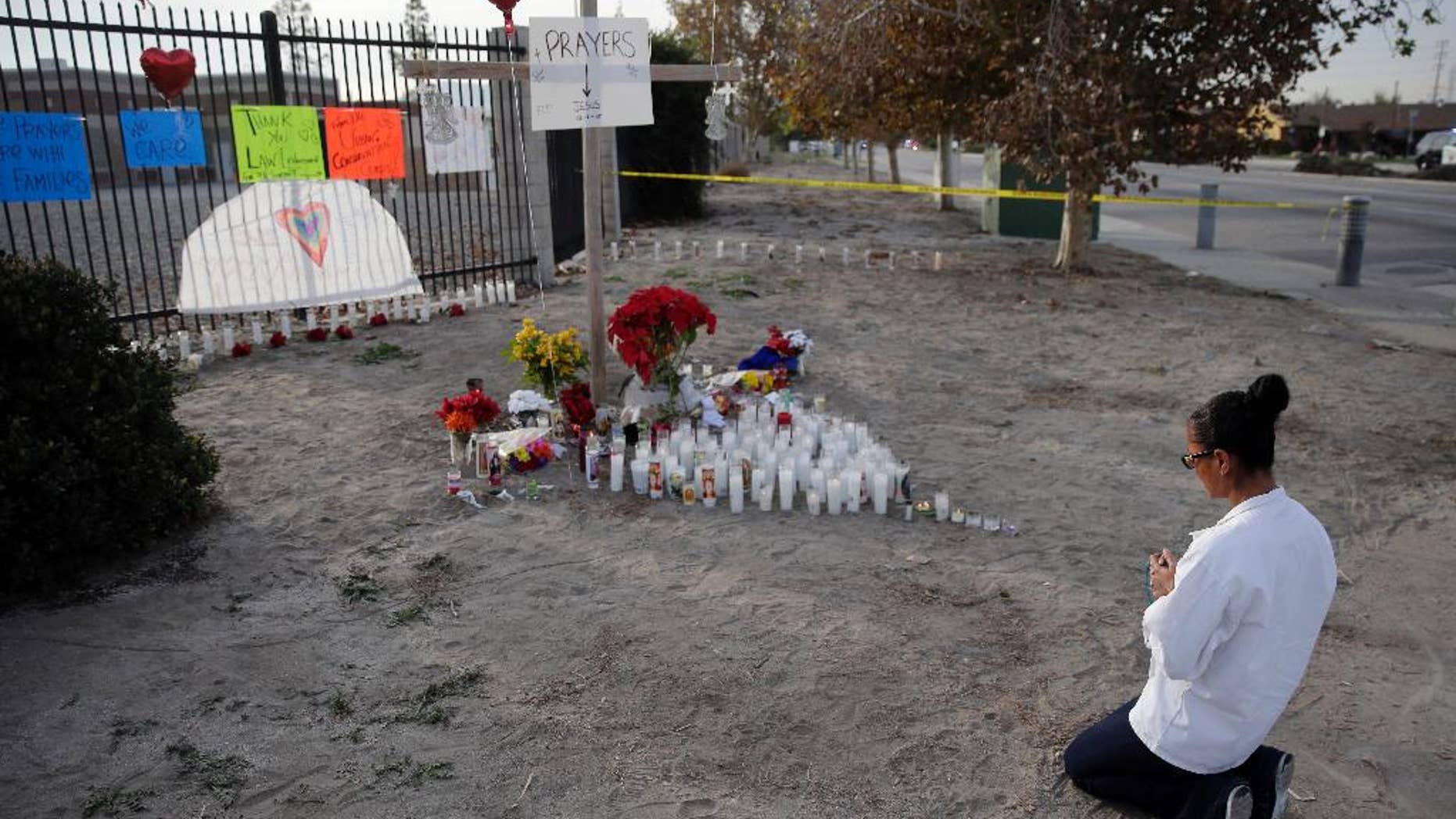 Melissa Smith prays at a makeshift memorial on Friday, Dec. 4, 2015, in San Bernardino, Calif. A husband and wife on Wednesday, dressed for battle and carrying assault rifles and handguns, opened fire on a holiday banquet for his co-workers, killing multiple people and seriously wounding others in a precision assault, authorities said. Hours later, the couple died in a shootout with police. (AP Photo/Chris Carlson)