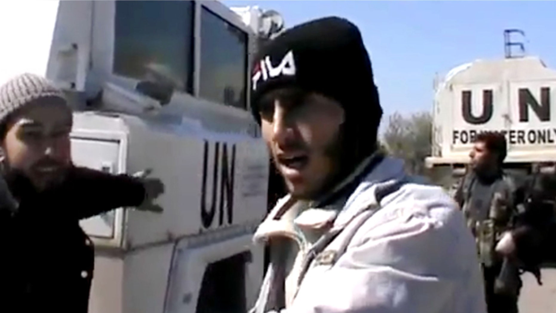 In this Wednesday, March 6, 2013 image taken from video obtained from the Ugarit News, which has been authenticated based on its contents and other AP reporting, Free Syrian Army fighters stand next to United Nations Disengagement Observer vehicles near Golan Heights in the southern province of Daraa, Syria.