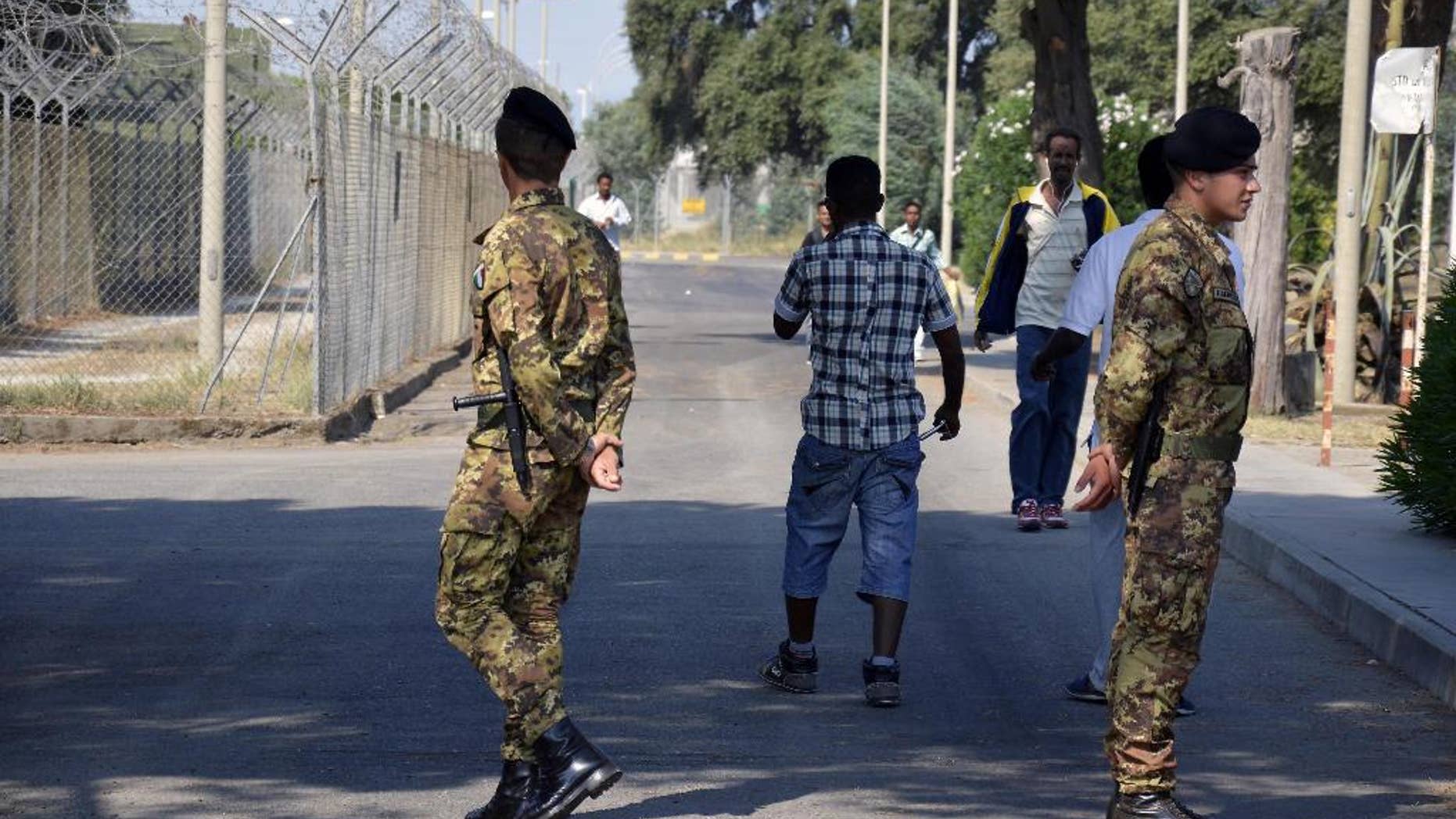 In this photo taken on August 21, 2013 soldiers patrol the Isola di Capo Rizzuto migrant center, near Crotone, Southern Italy. Italian police on Monday, May 15, 2017 arrested 68 people, including a priest and the head of a Catholic volunteer group called "Mercy," accusing them of being in cahoots with a major mafia clan that skimmed millions in public funds destined for one of Italy's biggest migrant welcome centers. Investigators said the Arena clan of the Calabrian 'ndrangheta mob had secured a lock on servicing the Isola di Capo Rizzuto migrant center near Crotone for the past decade. (Francesco Arena/ANSA via AP)