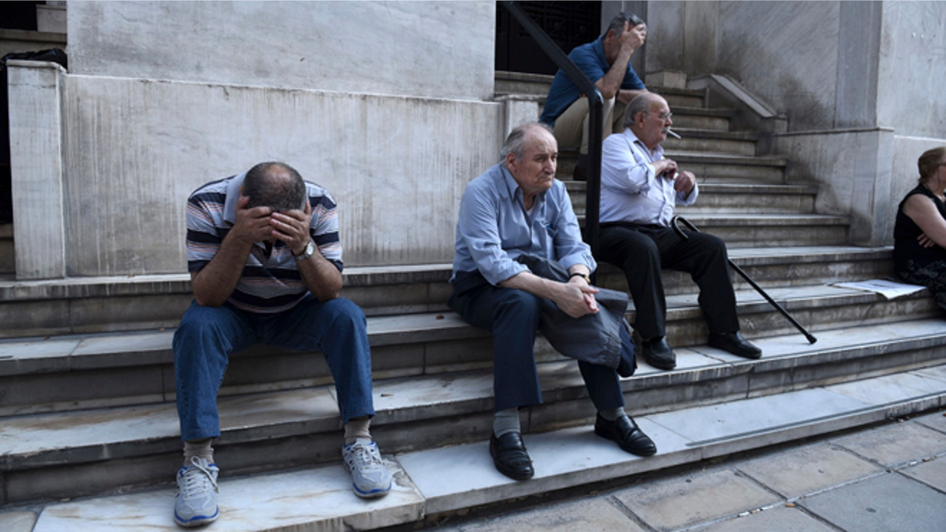 Elderly people, who usually get their pensions at the end of the month, wait outside a closed bank in the northern Greek port city of Thessaloniki, Monday, June 29, 2015. Greece's five-year financial crisis took its most dramatic turn yet, with the cabinet deciding that Greek banks would remain shut for six business days and restrictions would be imposed on cash withdrawals. (AP Photo/Giannis Papanikos)