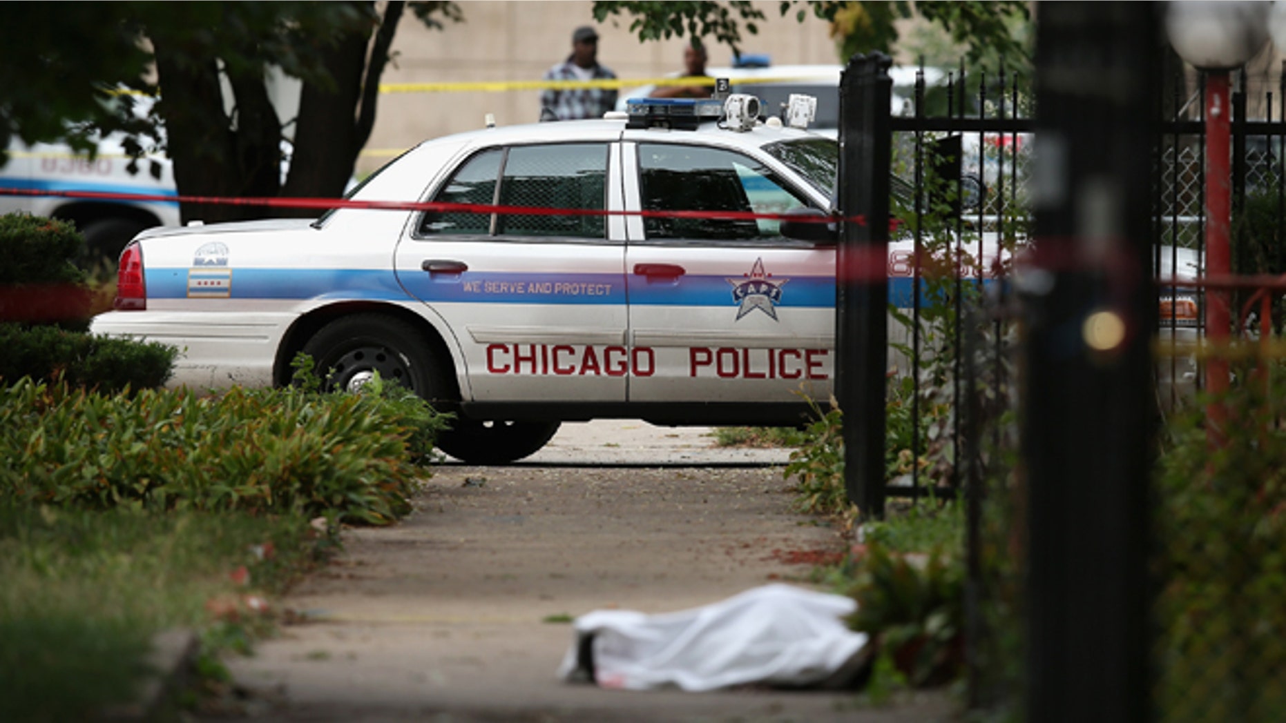 Police investigate the shooting death of 14-year-old Tommy McNeal, whose body is covered by a sheet on the sidewalk on September 20, 2013 in Chicago, Illinois. (Photo by Scott Olson/Getty Images)