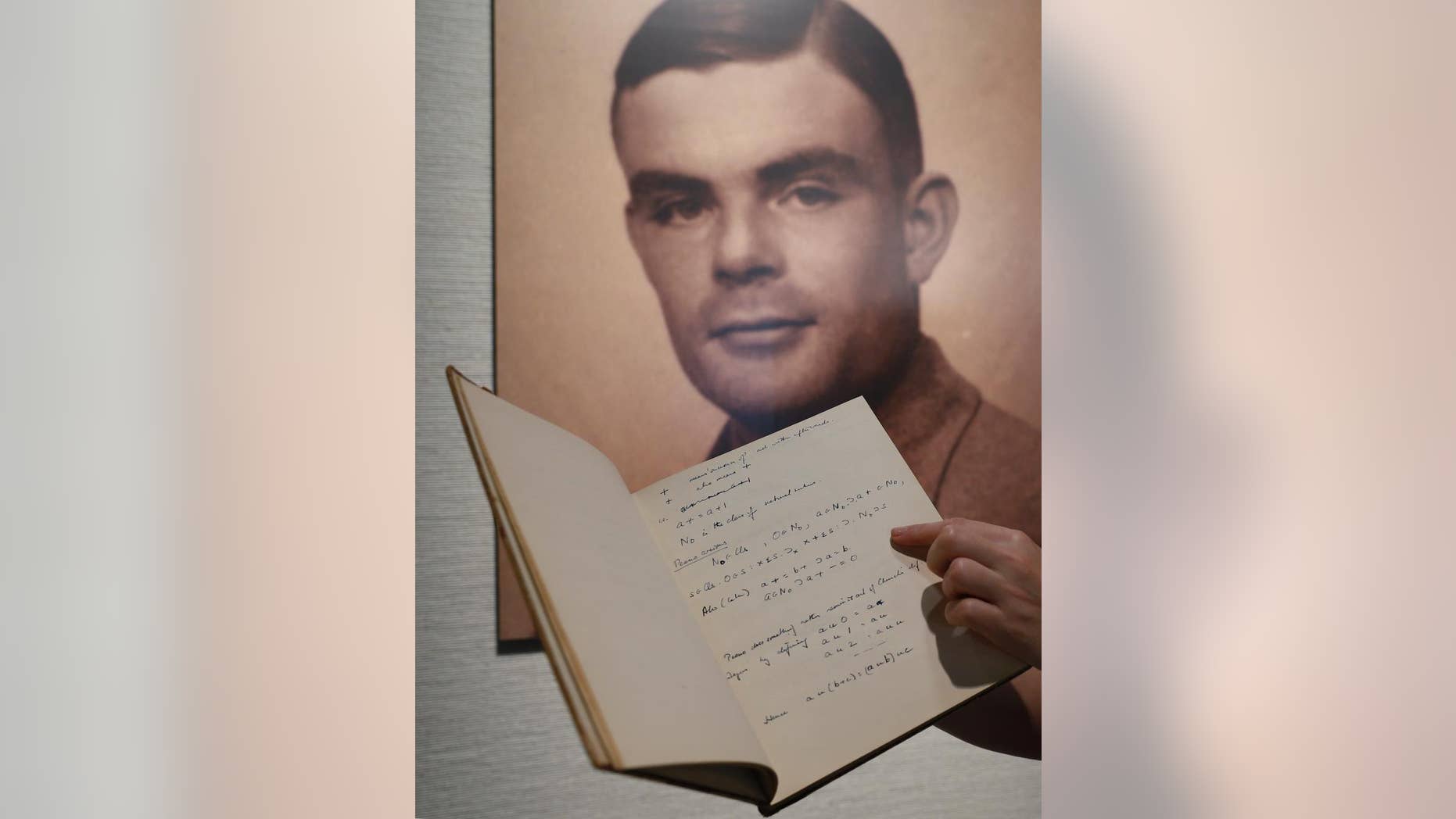 FILE - In this March 19, 2015 file photo, a page from the notebook of Alan Turing, the World War II code-breaking genius, is displayed in front of his portrait at an auction preview in Hong Kong. Turing, who was convicted of indecency in 1952 for being gay and later killed himself, was awarded a posthumous royal pardon in 2013. Britain's government announced Thursday, Oct. 20, 2016, that it will posthumously pardon thousands of gay and bisexual men convicted under the long-repealed anti-gay laws. (AP Photo/Kin Cheung, File)