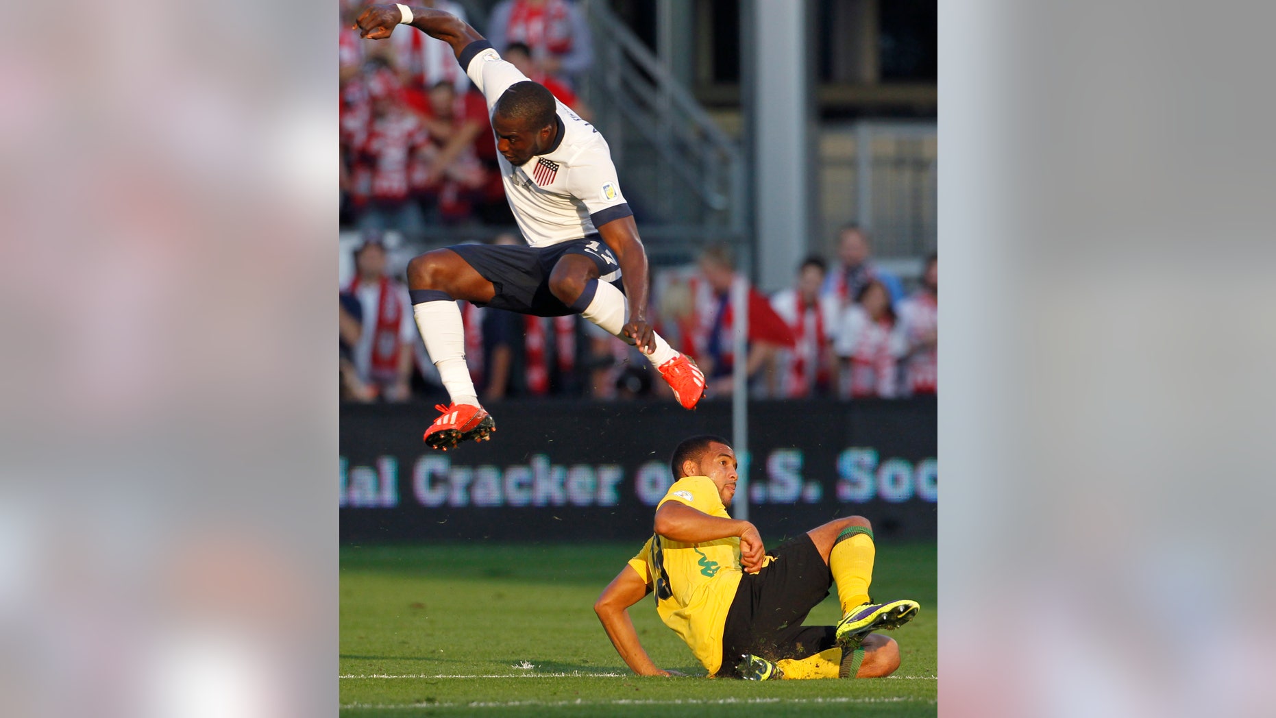 U.S. forward Jozy Altidore, top, jumps to avoid Jamaica defender Adrian Mariappa during the first half of a World Cup qualifier soccer match at Sporting Park in Kansas City, Kan., Friday, Oct. 11, 2013. (AP Photo/Colin E. Braley)