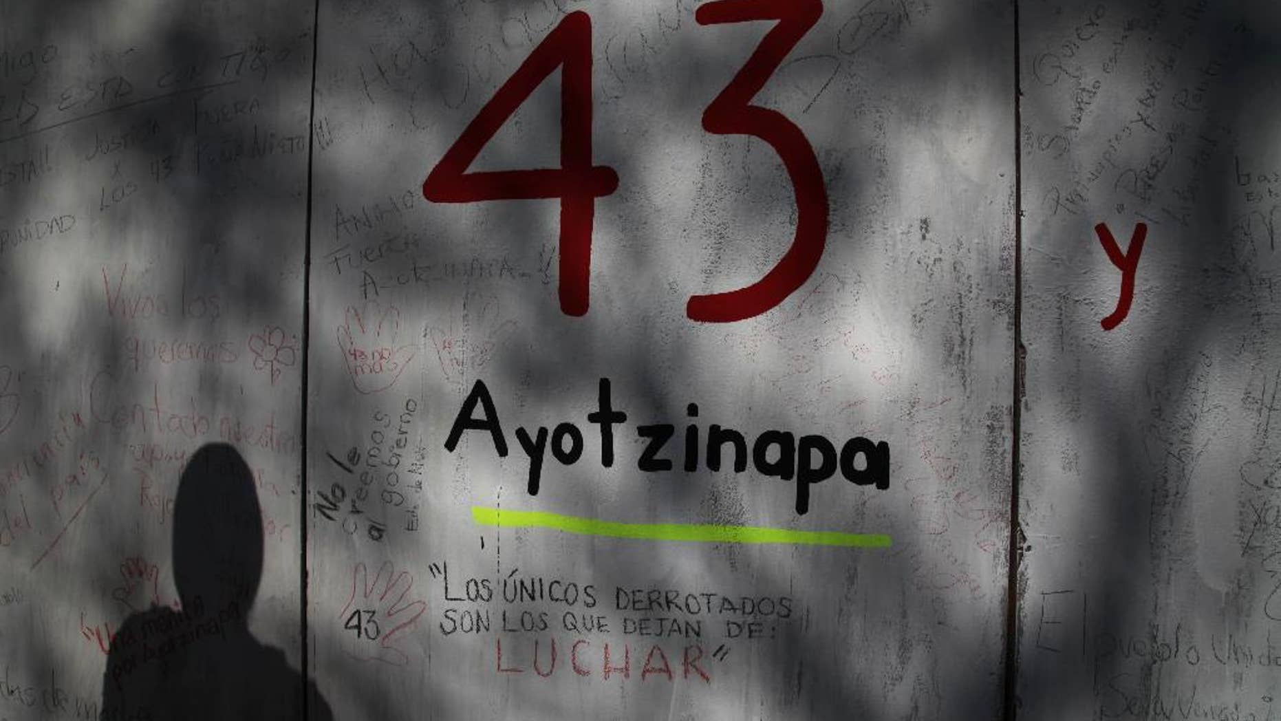 FILE - In this Dec. 28, 2014 file photo, the shadow of a demonstrator is cast on a wall with graffiti protesting the disappearance of 43 rural college students, in front of the Mexican Attorney General's office, in Mexico City. Mexican prosecutors said Tuesday, Jan. 20, 2015, that an Austrian forensics lab has been unable to find any more DNA that could be used by conventional means to identify charred remains that might be those of missing college students, but said they have authorized a final, unconventional effort. (AP Photo/Marco Ugarte, File)