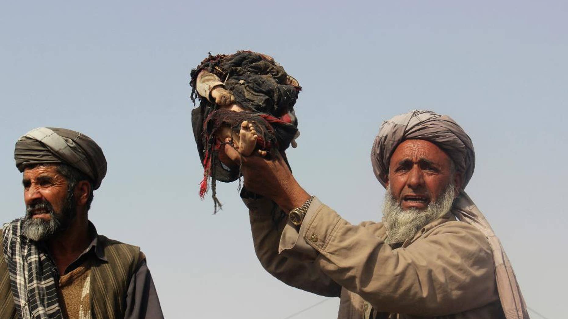 An Afghan man holds up the body of a child that was killed during clashes between Taliban and Afghan security forces in Kunduz province north of Kabul, Afghanistan, Thursday, Nov. 3, 2016, Authorities say a joint raid by U.S. and Afghan forces targeting senior Taliban commanders killed two American service members and 26 civilians. Afghan officials said they were still investigating the attack and its civilian casualties, some of which may have been caused by the airstrikes. (AP Photo/Najim Rahim)