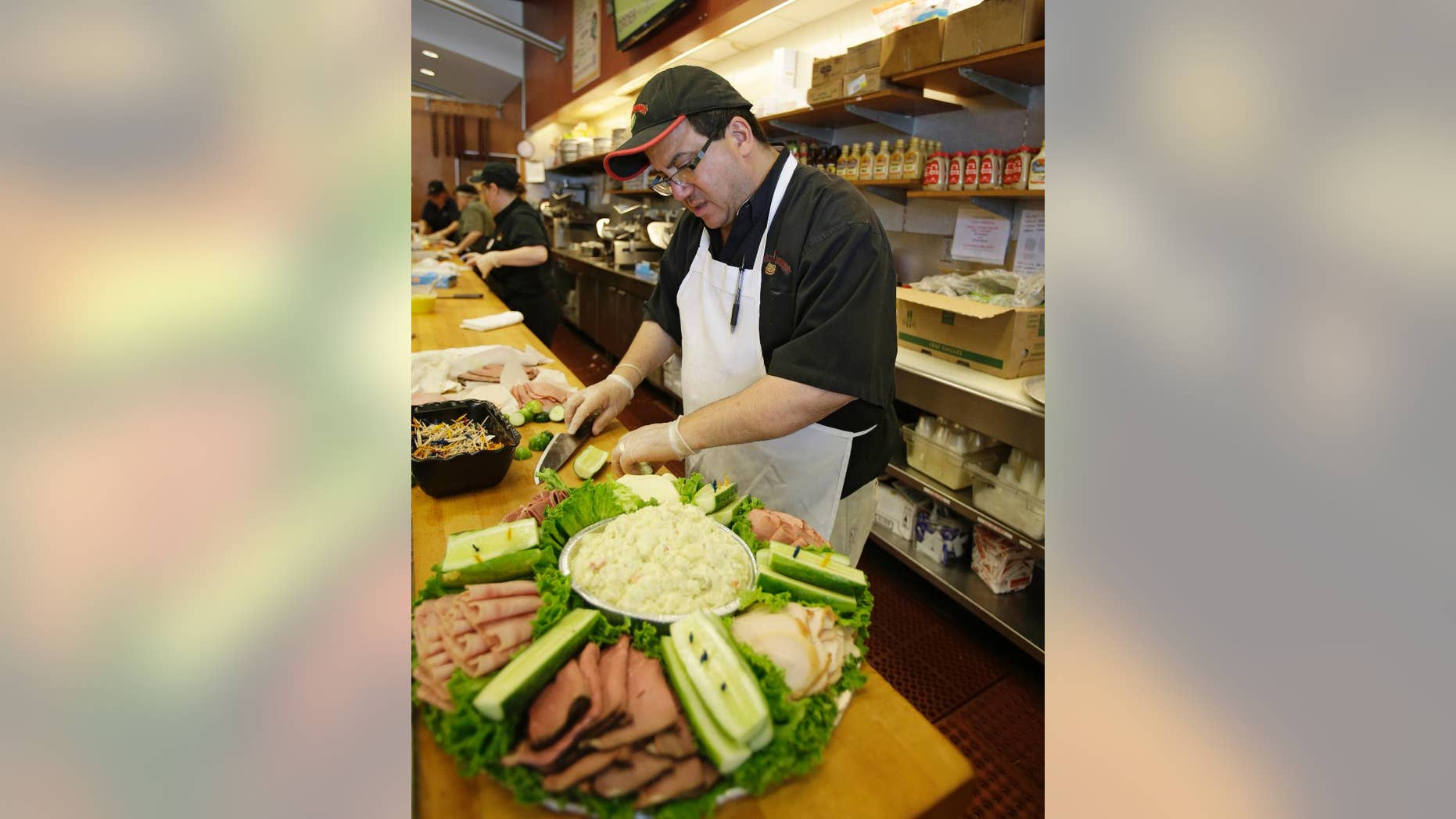 In this Friday, June 6, 2014 photo, Kenny Kurland prepares a deli meat and cheese platter at Corky & Lenny's Restaurant & Deli in Woodmere Village, Ohio. The University of Michigan issues its index of consumer sentiment for July on Friday, Aug. 1, 2014. (AP Photo/Tony Dejak)