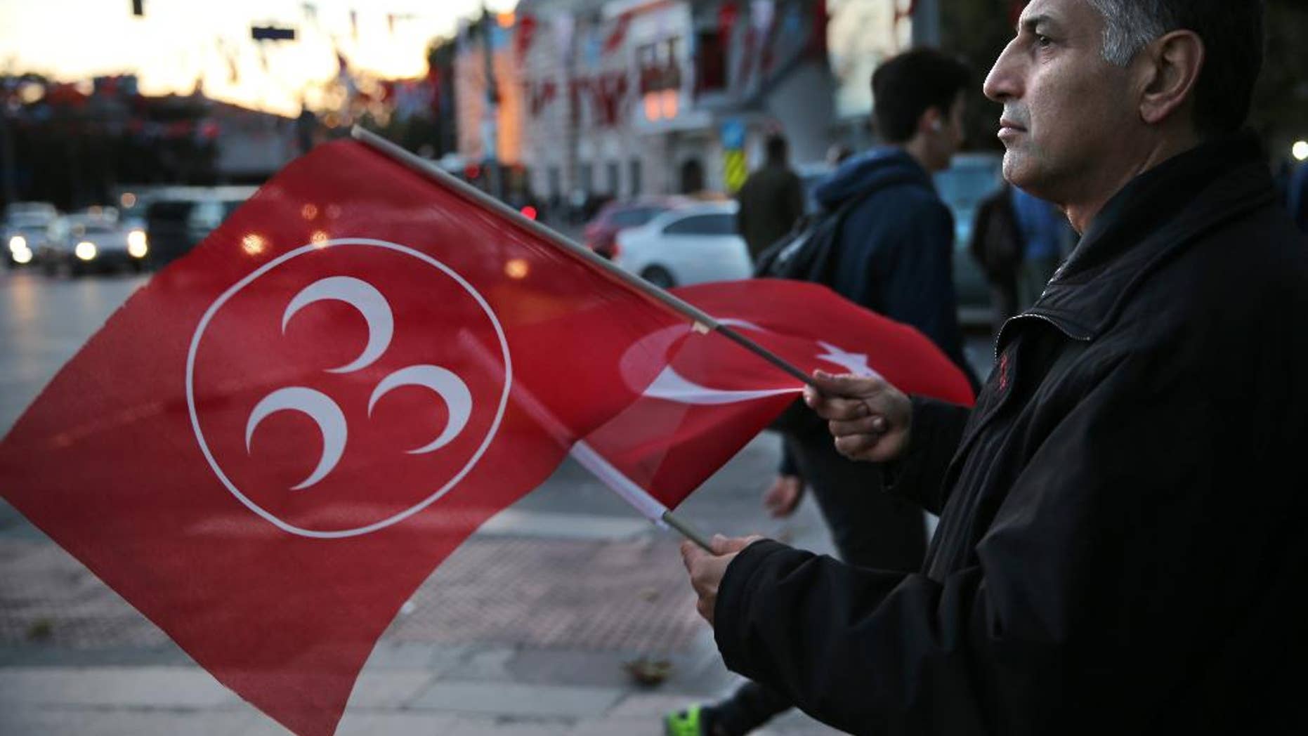 A supporter of Turkey's opposition Nationalist Action Party, (MHP), waves his party and nation flags, in Istanbul, Saturday, Oct. 31, 2015. Turkish political parties have made their closing appeals ahead of Sunday Nov. 1 crucial parliamentary general election vote. (AP Photo/Hussein Malla)