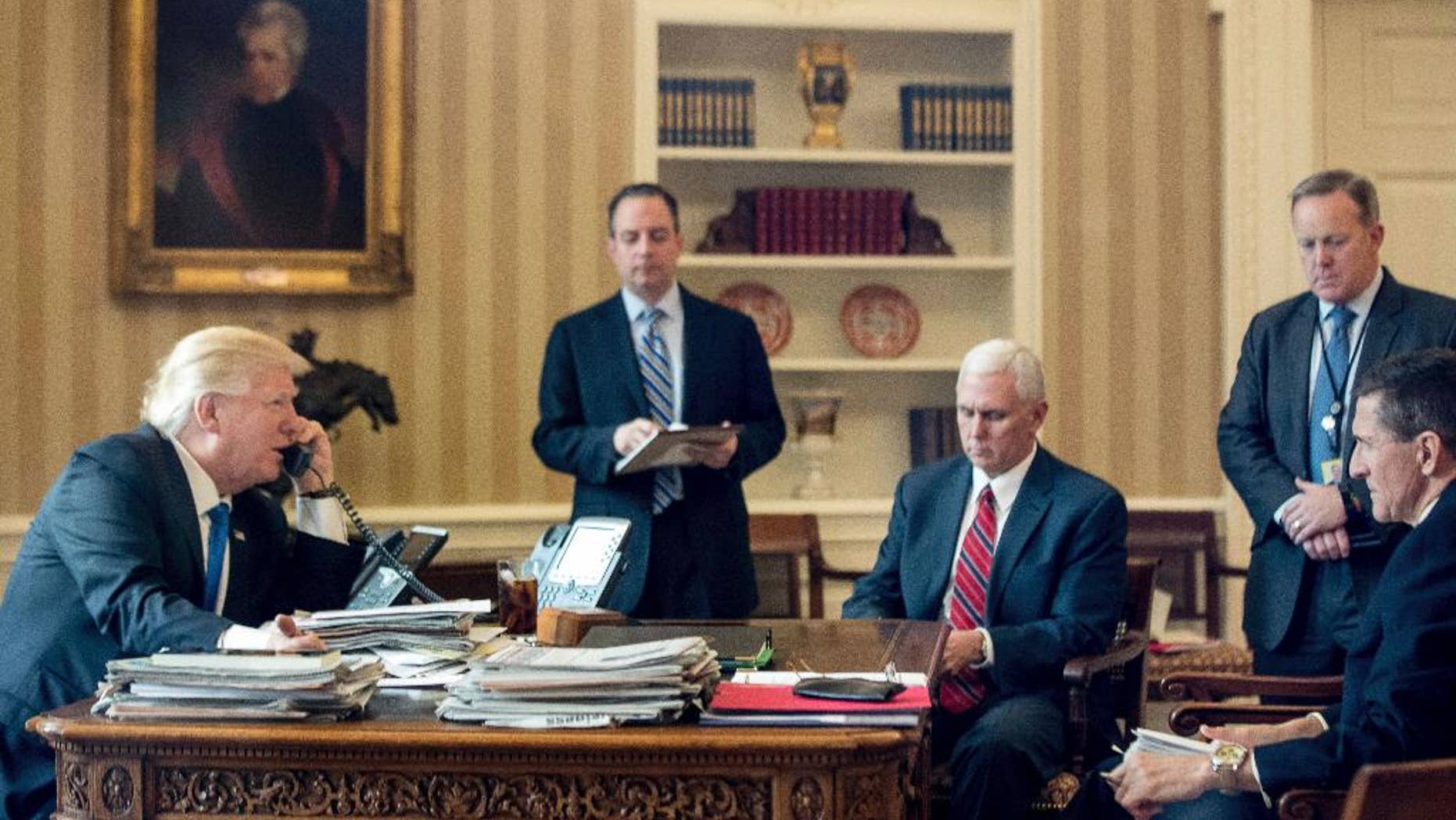 President Donald Trump, accompanied by, from second from left, Chief of Staff Reince Priebus, Vice President Mike Pence, White House press secretary Sean Spicer and National Security Adviser Michael Flynn, speaks on the phone with with Russian President Vladimir Putin, Saturday, Jan. 28, 2017, in the Oval Office at the White House in Washington. (AP Photo/Andrew Harnik)