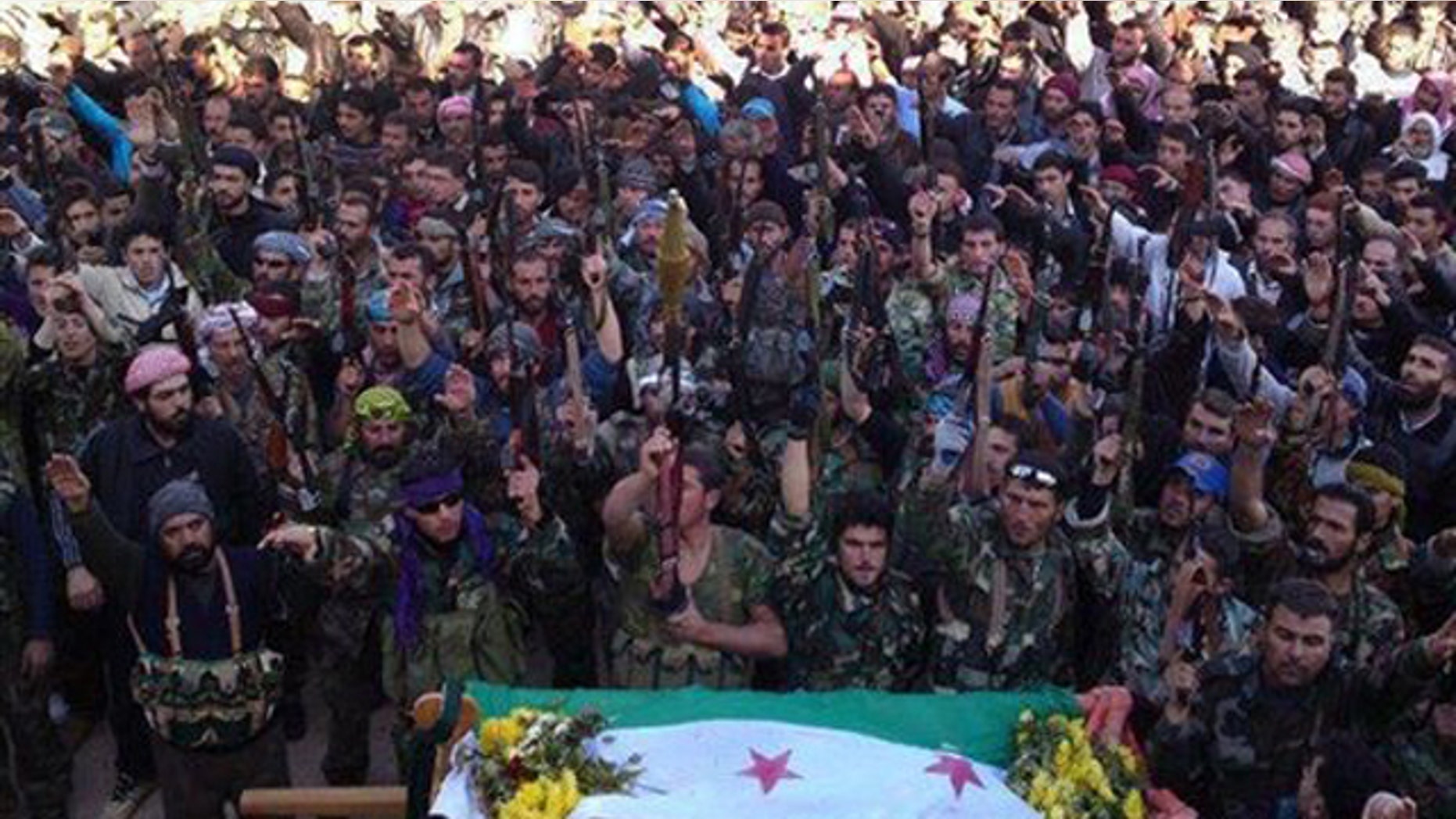 Feb. 2, 2012: In this image, provided by the Local Coordination Committees in Syria, Syrian rebels raise their weapons as they attend a funeral procession of their comrade, whose dead body, front, is seen wrapped by the Syrian revolution flag, in Edleb, north Syria.