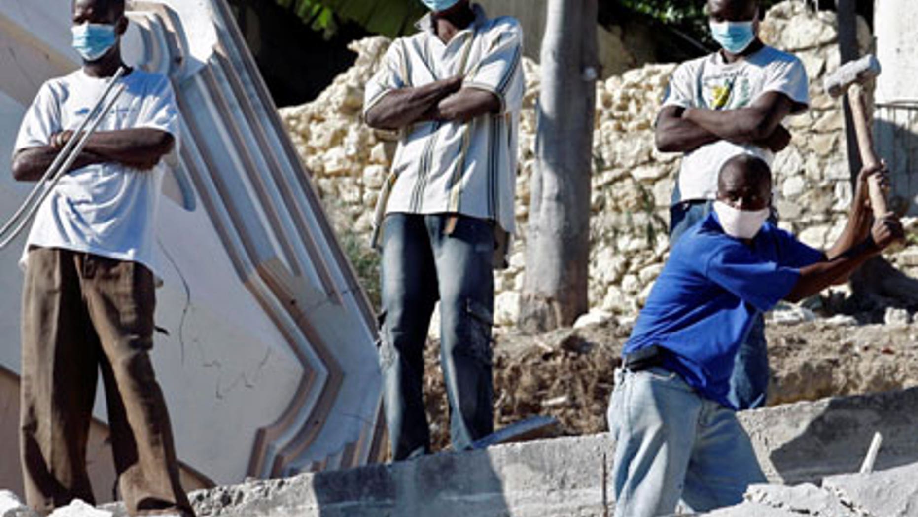 Jan. 14: Young men stand watch as another digs through debris in the shattered Haitian capital of Port-au-Prince. Tensions are rising as aid slowly filters in.