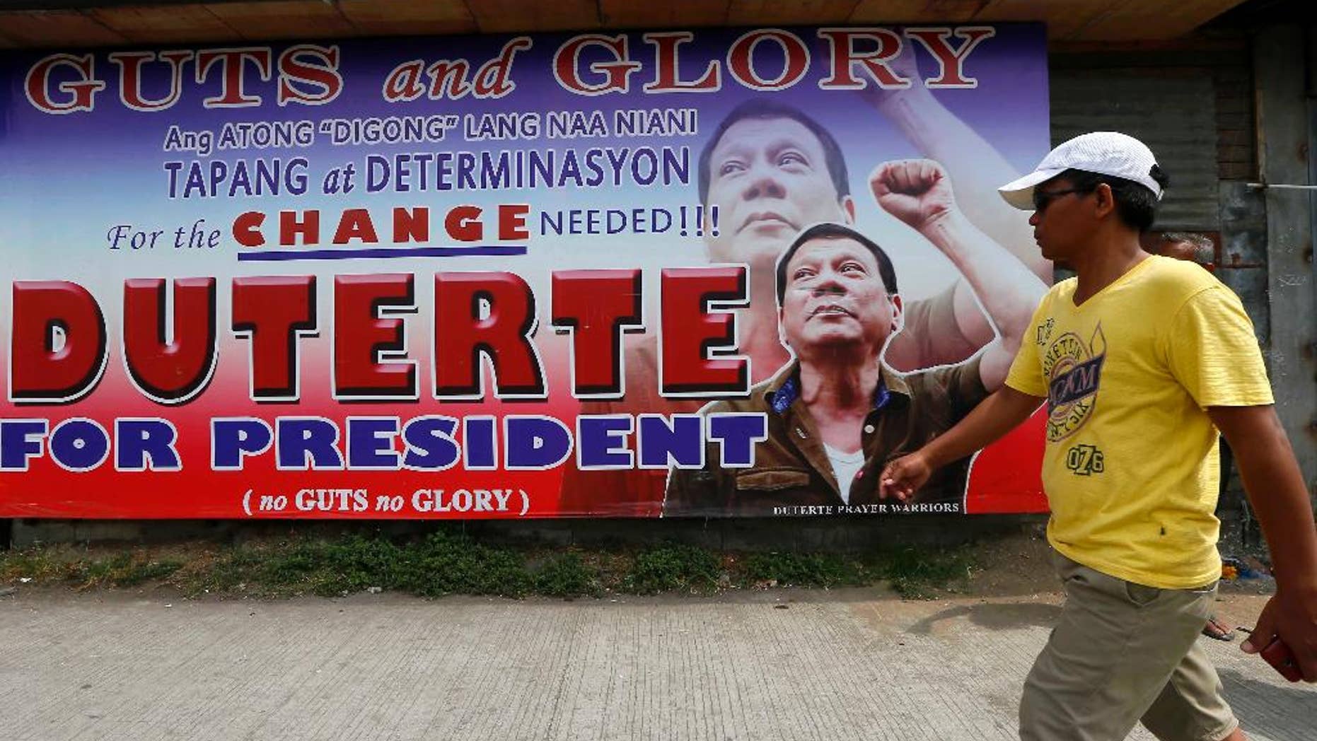 A resident walks past a campaign billboard of leading presidential candidate Mayor Rodrigo Duterte along a boulevard at his hometown in Davao city in southern Philippines Wednesday, May 11, 2016. Duterte has widened his lead in unofficial tally but still refuses to claim victory.(AP Photo/Bullit Marquez)