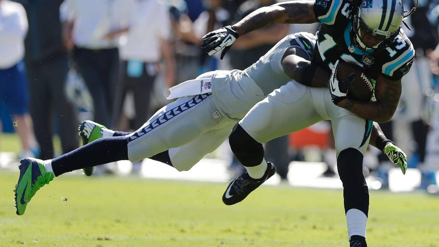 Carolina Panthers wide receiver Kelvin Benjamin (13) moves as Seattle Seahawks strong safety Kam Chancellor (31) tackles during the first half of an NFL football game, Sunday, Oct. 26, 2014, in Charlotte. (AP Photo/Chuck Burton)