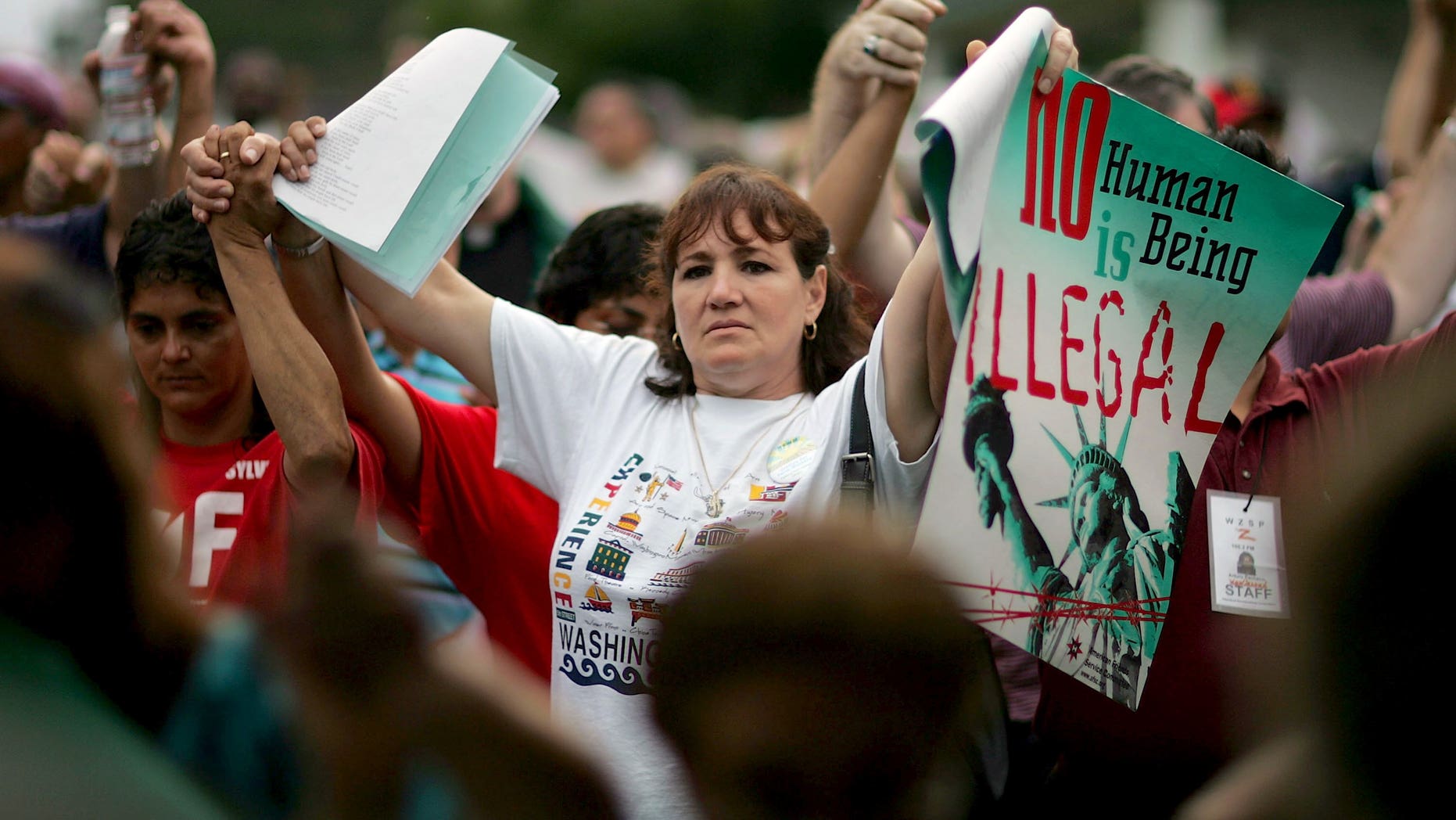 AVON PARK, FL - JULY 23: Rosa Semeraro from Tampa, Florida joins hands with others as they protest against a proposed municipal ordinance that would crack down on illegal immigration July 23, 2006 in Avon Park, Florida. Tom Macklin, the mayor of Avon Park, proposed to fine landlords for renting to illegal immigrants, to take away business permits from any company that knowingly employed illegals, and to locally set English as the official language within Avon Park. The Avon Park City Council is scheduled to take a final vote on the ordinance tomorrow. (Photo by Joe Raedle/Getty Images)