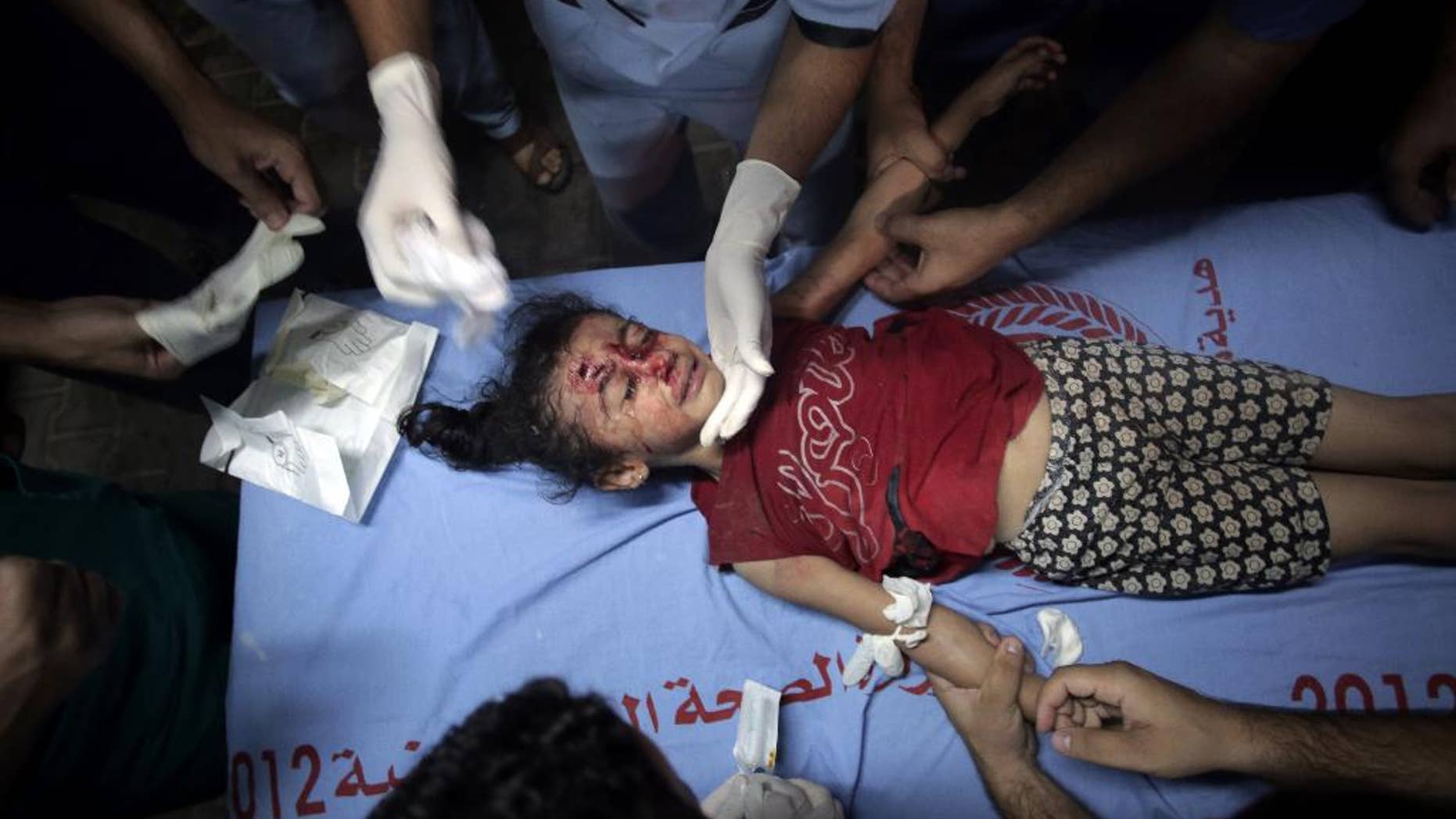 Palestinian medics treat a wounded girl, at the Kuwaiti hospital at Rafah refugee camp, in southern Gaza Strip, Monday, Aug. 4, 2014. Israel withdrew most of its ground troops from the Gaza Strip on Sunday in an apparent winding down of the nearly monthlong operation against Hamas that has left more than 1,800 Palestinians and more than 60 Israelis dead. (AP Photo/Khalil Hamra)