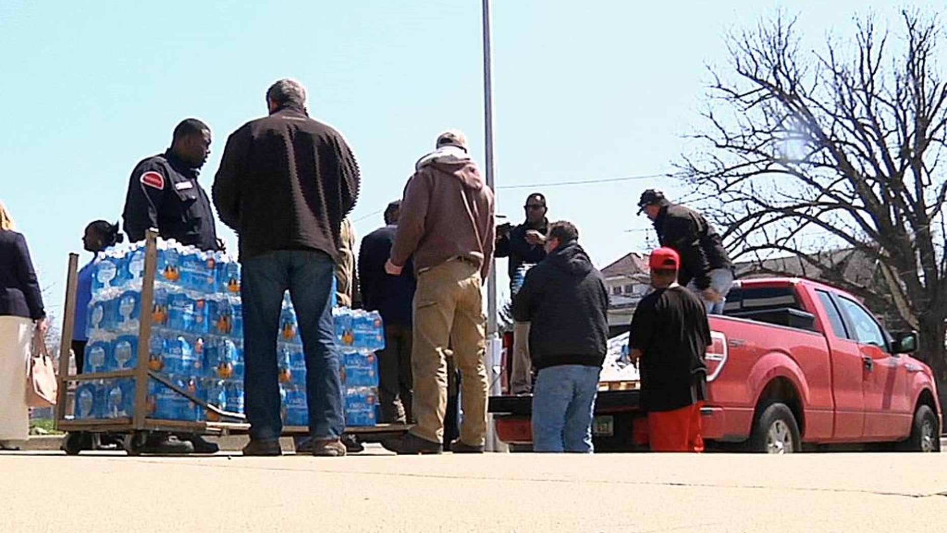 In this image made from video, volunteers from the United Auto Workers-Ford and other volunteers unload cases of water outside Sampson-Webber Leadership Academy in Detroit on Thursday, April 14, 2016. The academy is one of 19 schools in Detroit's school district that were found to have elevated levels of lead or copper in their water. (AP Photo/Mike Householder)