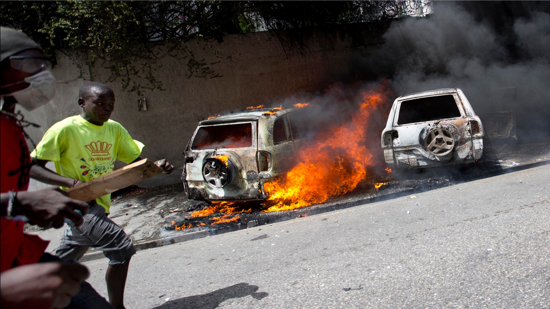 People run after cars were set on fire near the Best Western hotel during protests over a fuel price increase in Port-au-Prince, Haiti, on Saturday, July 7, 2018.