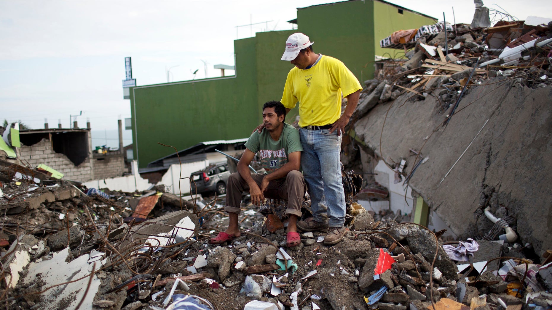 Roberto Ganchoso is comforted by a neighbor as he sits on what's left of his neighborhood, as he watches a bulldozer demolish the hotel next door to his property in Pedernales, Ecuador, Saturday, April 23, 2016. President Rafael Correa has said the earthquake caused $3 billion in damage and warned that the reconstruction effort will take years. His administration is temporarily raising taxes to fund the recovery. (AP Photo/Rodrigo Abd)