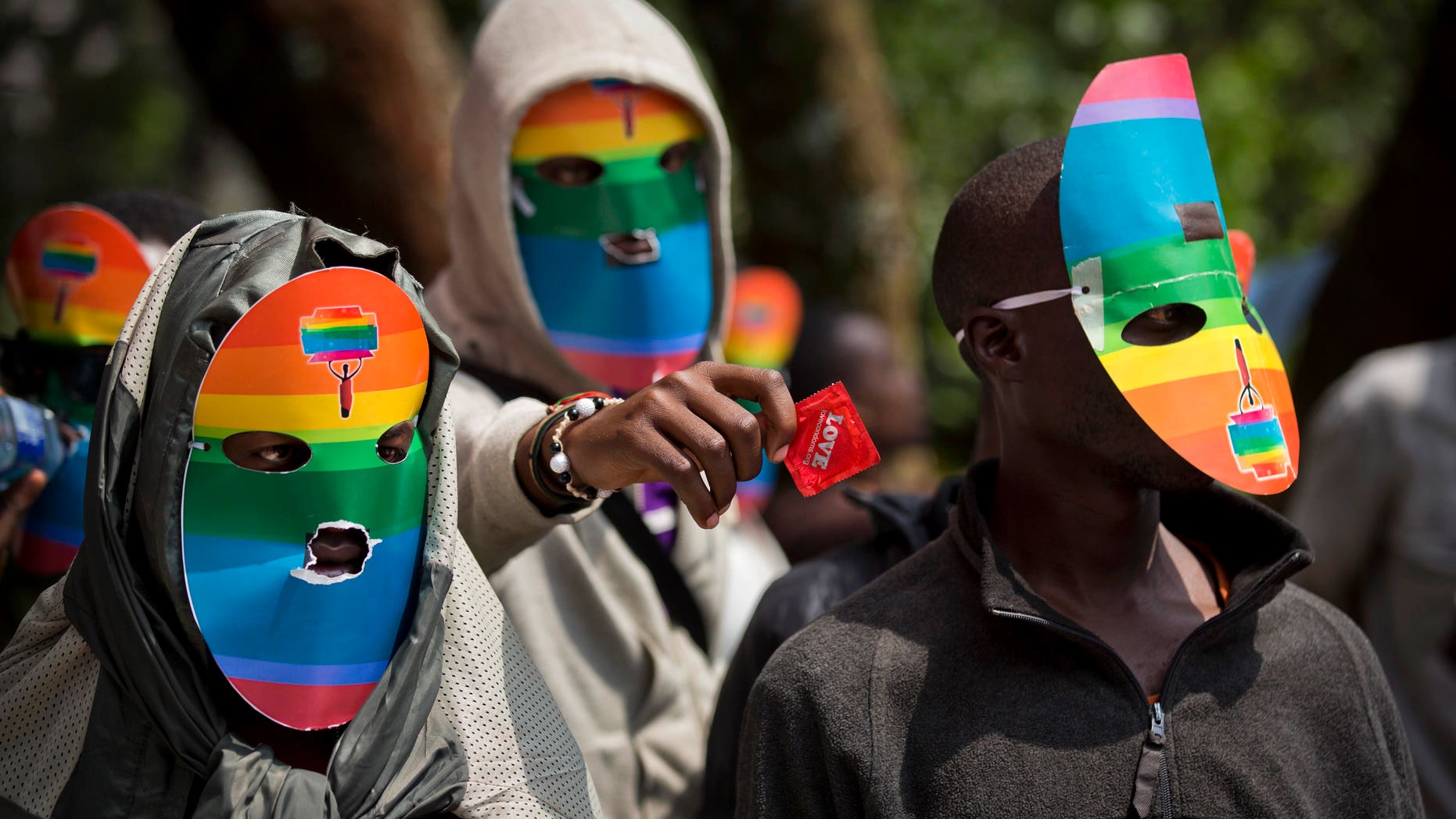 FILE - In this Monday, Feb. 10, 2014 file photo, Kenyan gays and lesbians and others supporting their cause wear masks to preserve their anonymity and one holds out a condom, as they stage a rare protest, against Uganda's increasingly tough stance against homosexuality and in solidarity with their counterparts there, outside the Uganda High Commission in Nairobi, Kenya. Uganda's President Yoweri Museveni is expected to sign Monday, Feb. 24, 2014 a controversial anti-gay bill that allows harsh penalties for homosexual offenses, a bill which rights groups have condemned as draconian in a country where homosexuality is already illegal. (AP Photo/Ben Curtis, File)