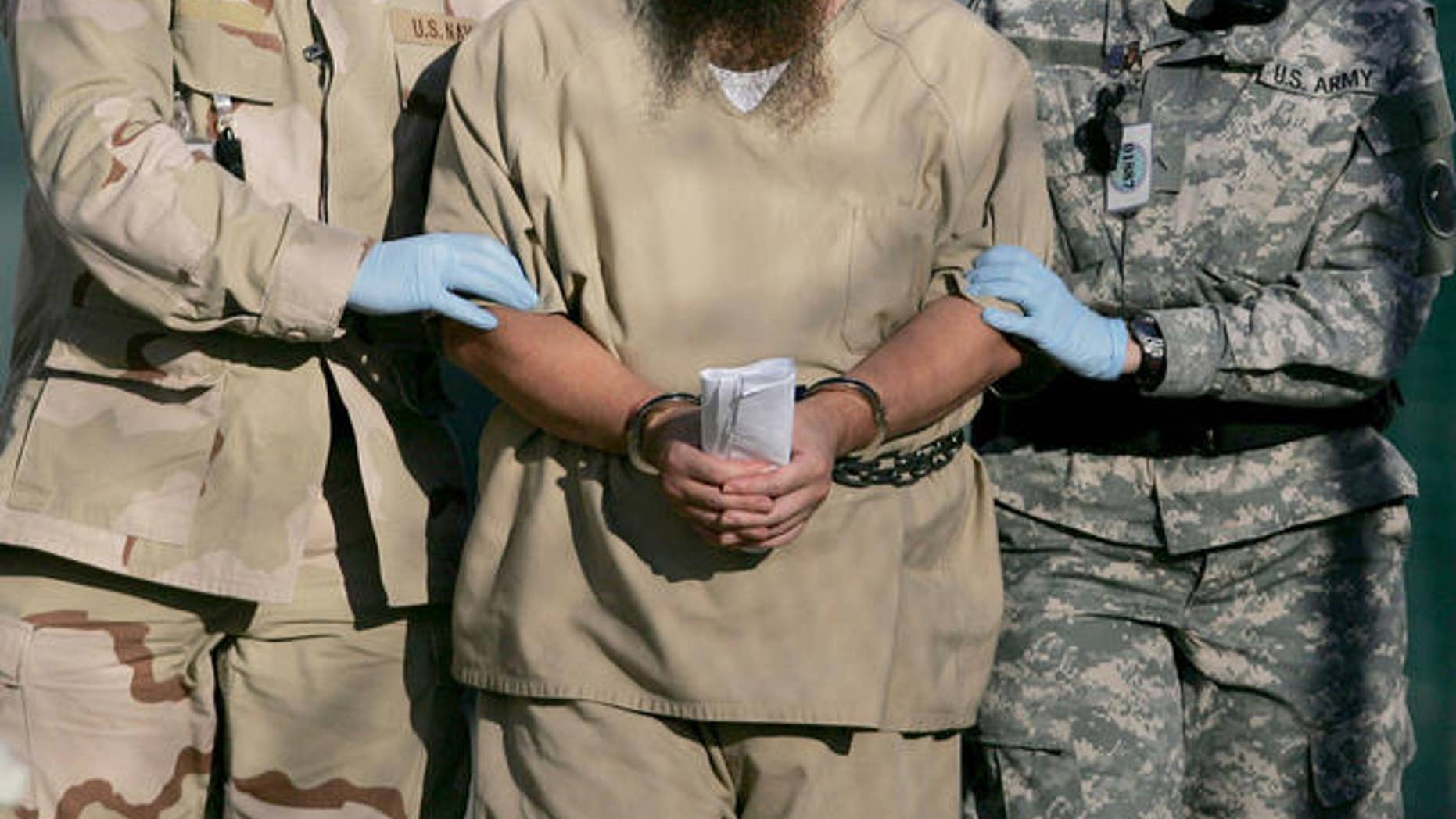 In this photo, reviewed by a U.S. Dept of Defense official, a shackled detainee is transported away from his annual Administrative Review Board hearing with U.S. officials, at Camp Delta detention center, Guantanamo Bay U.S. Naval Base, Cuba, Wednesday, Dec. 6, 2006. Each Guantanamo detainee has the option to participate in his own annual status review hearing which is part of the process for determining if a given detainee will continue to be held for another year. (AP Photo/Brennan Llinsley)