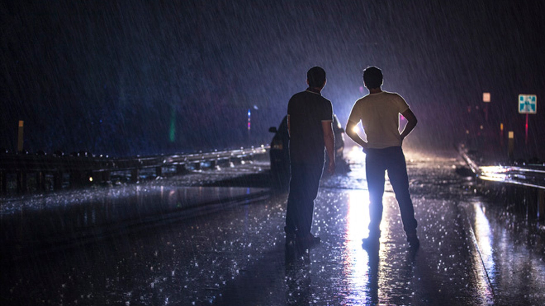 Two men stand on the Dry Creek bridge as they look on at a stranded vehicle from the rising flood water in Austin, Texas, early Friday morning, May 27, 2016. (Ricardo B. Brazziell/Austin American-Statesman via AP)