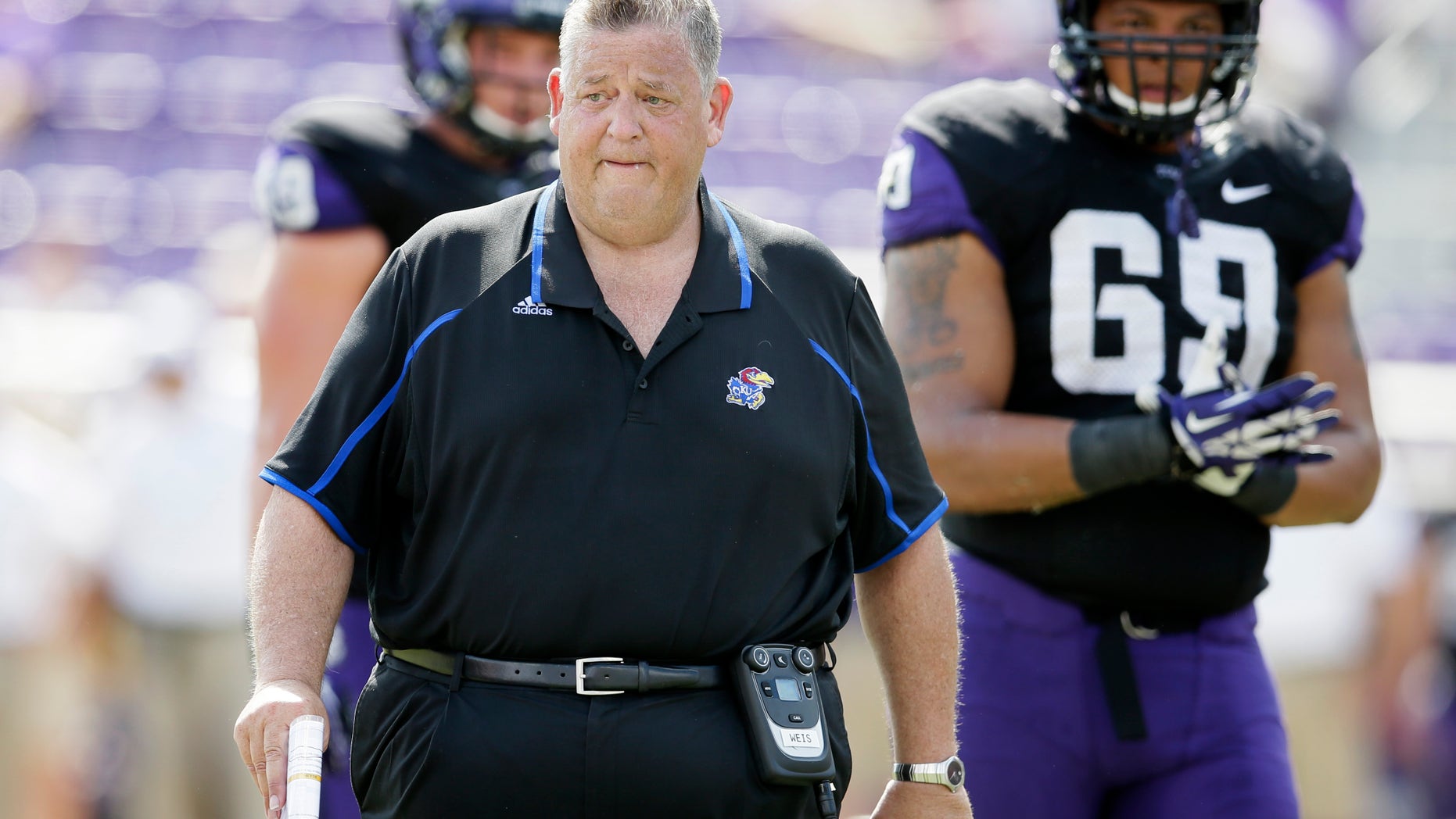 Kansas head coach Charlie Weis walks off the field after checking on an injured payer late in the second half of an NCAA college football game against TCU, Saturday, Oct. 12, 2013, in Fort Worth, Texas. Kansas defensive lineman Peter Gallo (69) watches int he 27-17 TCU win. (AP Photo/Tony Gutierrez)