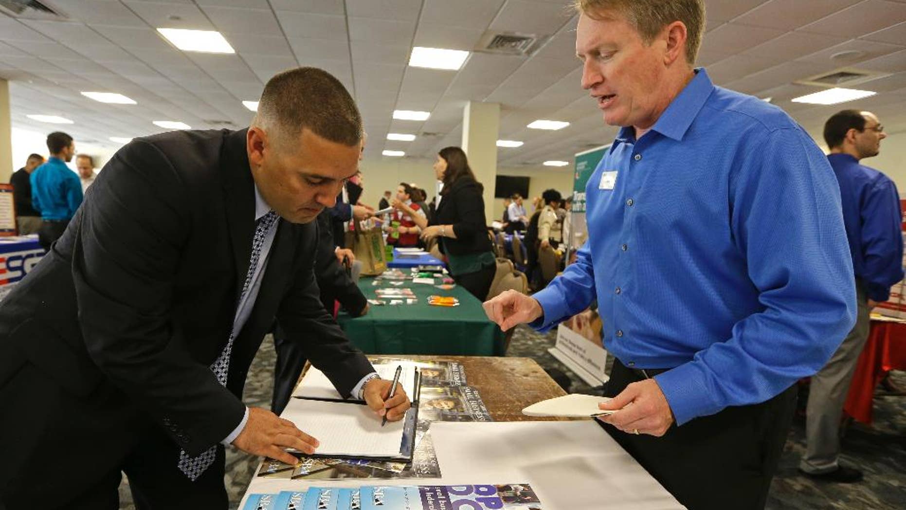 In this Friday, Feb. 6, 2015 photo, U.S. Marine Corps veteran Ignacio Yanes, left, writes information given by Jim Brooks, right, of the Small Business Administration at the annual Veterans Career and Resource Fair in Miami. The Labor Department issues its December report on job openings and labor turnover on Tuesday, Feb. 10, 2015. (AP Photo/Alan Diaz)