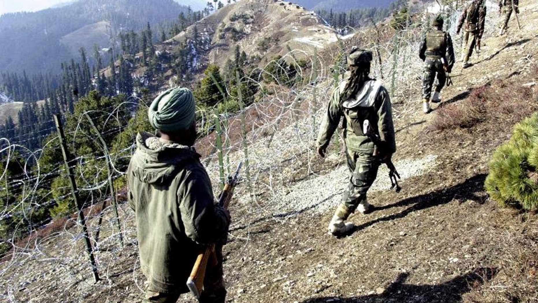 Indian soldiers on patrol along a barbed-wire fence in Baras, on December 4, 2003 -- near the Line of Control (LoC) that divides Kashmir