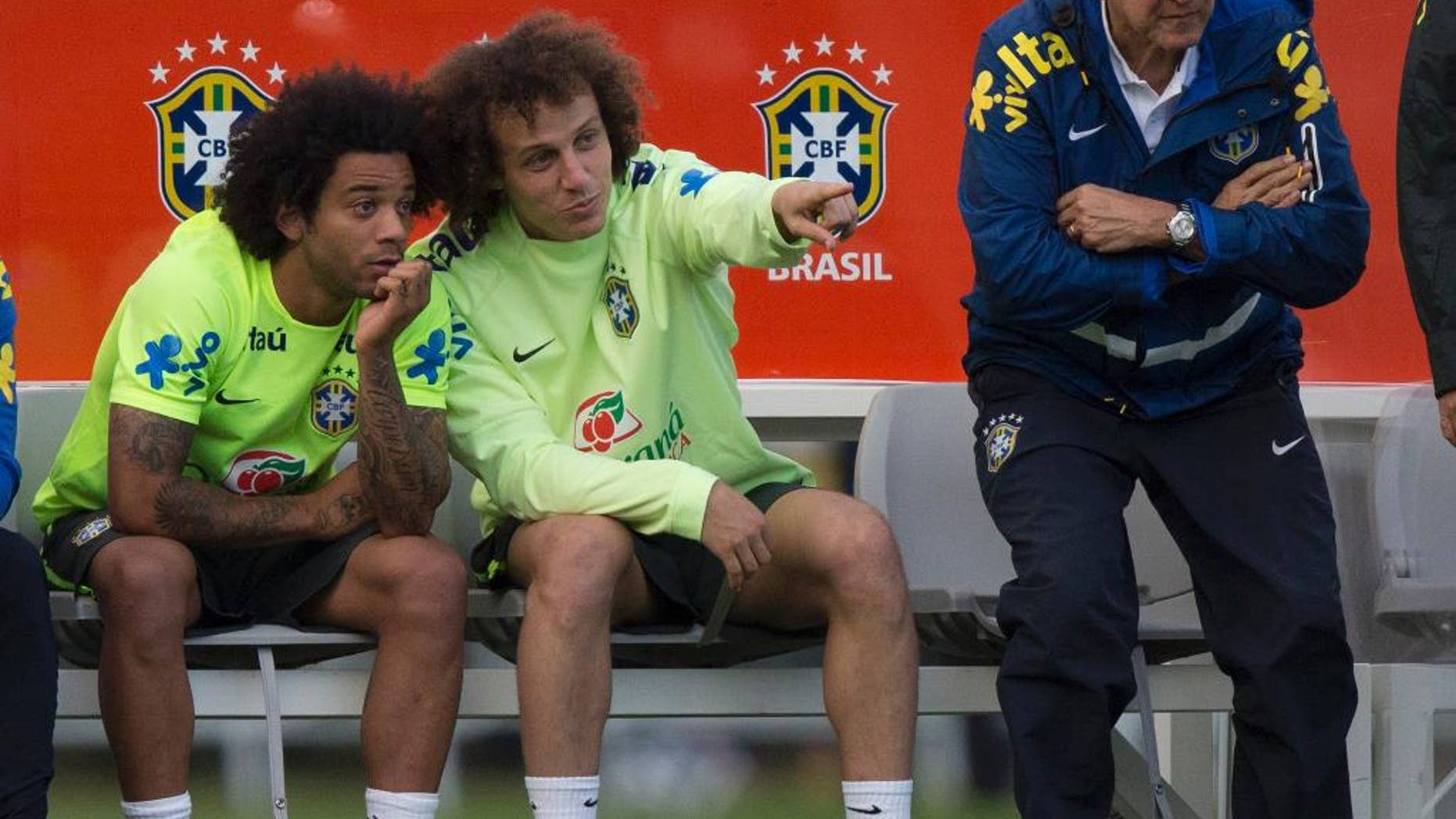 Brazil national soccer team members, David Luiz, center, talks with Marcelo, left, as the Brazil's team coordinator Carlos Alberto Parreira stands next to them, during a practice session at the Granja Comary training center, in Teresopolis, Brazil, Sunday, July 6, 2014. Brazil will face Germany in their World Cup semifinals' match, without superstar soccer player Neymar. (AP Photo/Leo Correa)
