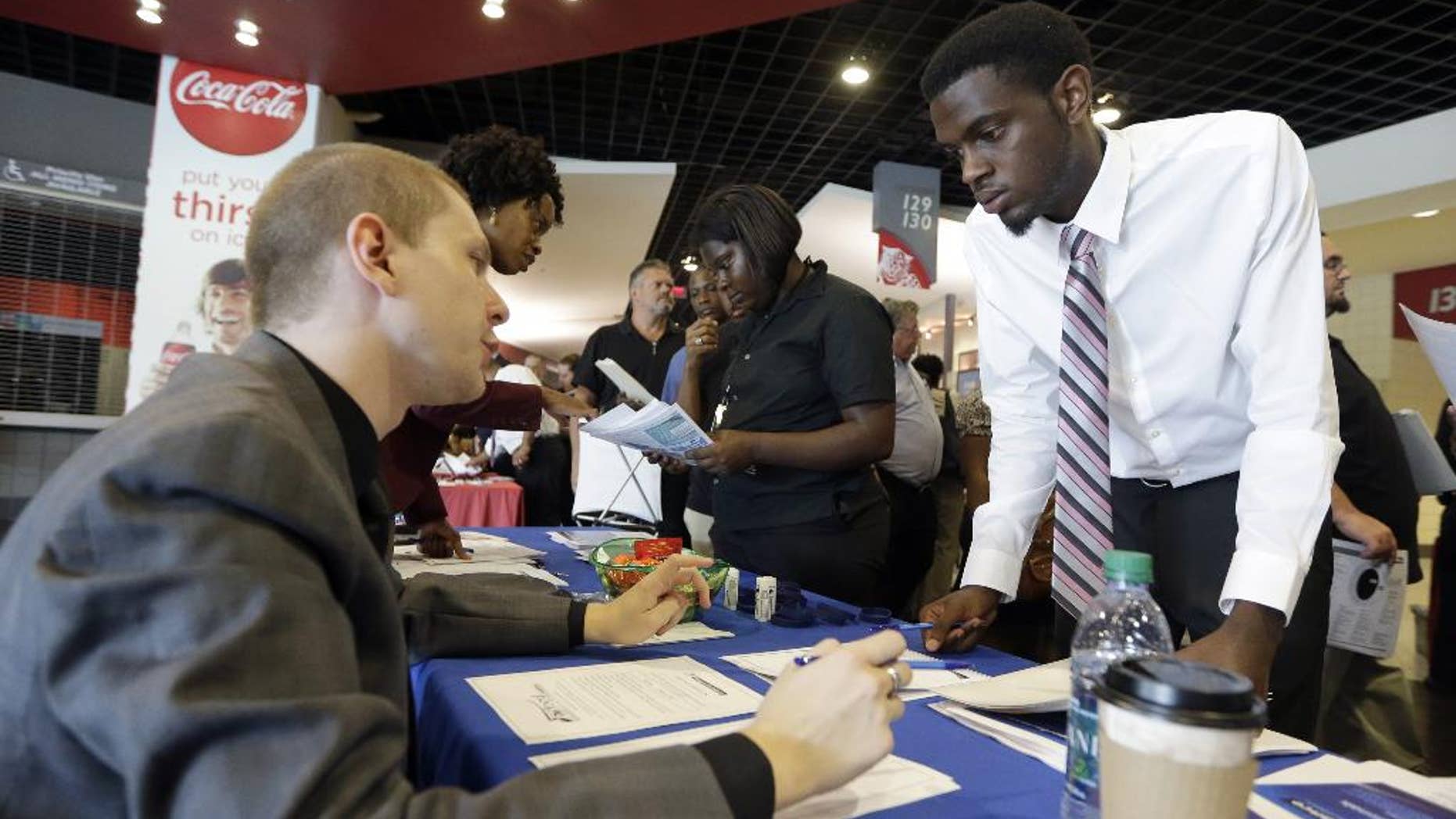 In this photo taken Wednesday, June 10, 2015, job seeker Cory McClain, right, listens to Sam Cucci, of Teleperformance, during a job fair in Sunrise, Fla. The Labor Department reports on the number of people who applied for unemployment benefits for the week ending June 13 on Thursday, June 18, 2015. (AP Photo/Alan Diaz)