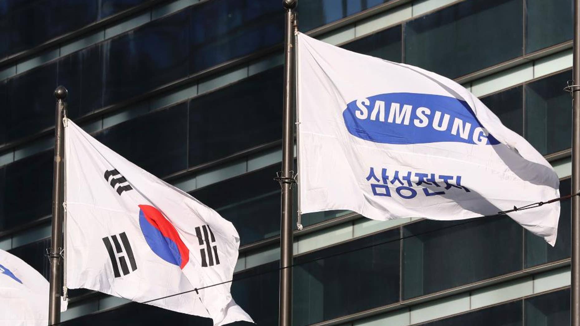 The company flag of Samsung Electronics flutters next to the South Korean national flag in Seoul, South Korea, Monday, Jan. 16, 2017. Prosecutors requested the arrest Monday of the de facto head of Samsung, South Korea's biggest company, on bribery and other charges in the influence-peddling scandal that led to the impeachment of the country's president. (AP Photo/Lee Jin-man)
