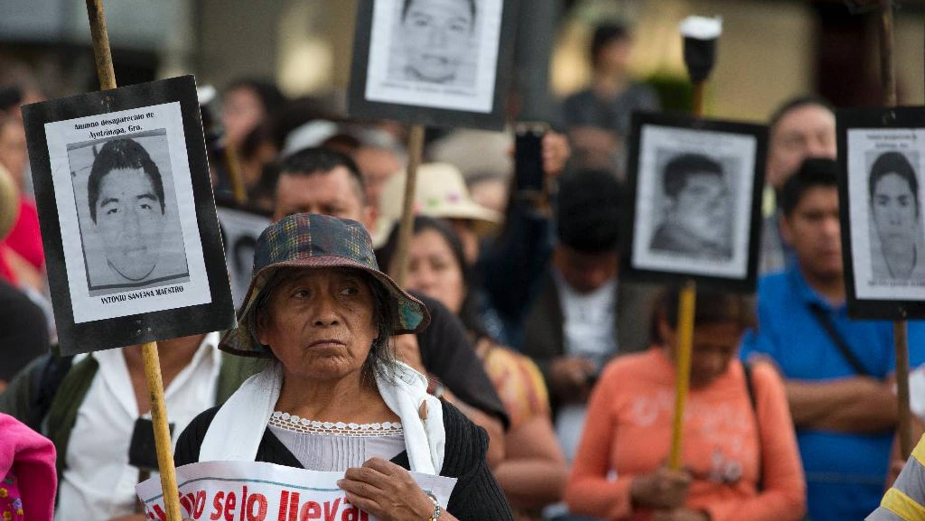 Family members of 43 missing teachers college students carry pictures of the students as they march with supporters to demand the case not be closed and that experts' recommendations about new leads be followed, in Mexico City, Tuesday, April 26, 2016. The U.N. Office of the High Commissioner for Human Rights said Tuesday that it is troubled by a group of international experts' complaints of obstacles to their investigation into Sept. 26, 2014 disappearance of the students in southern Guerrero State.(AP Photo/Rebecca Blackwell)