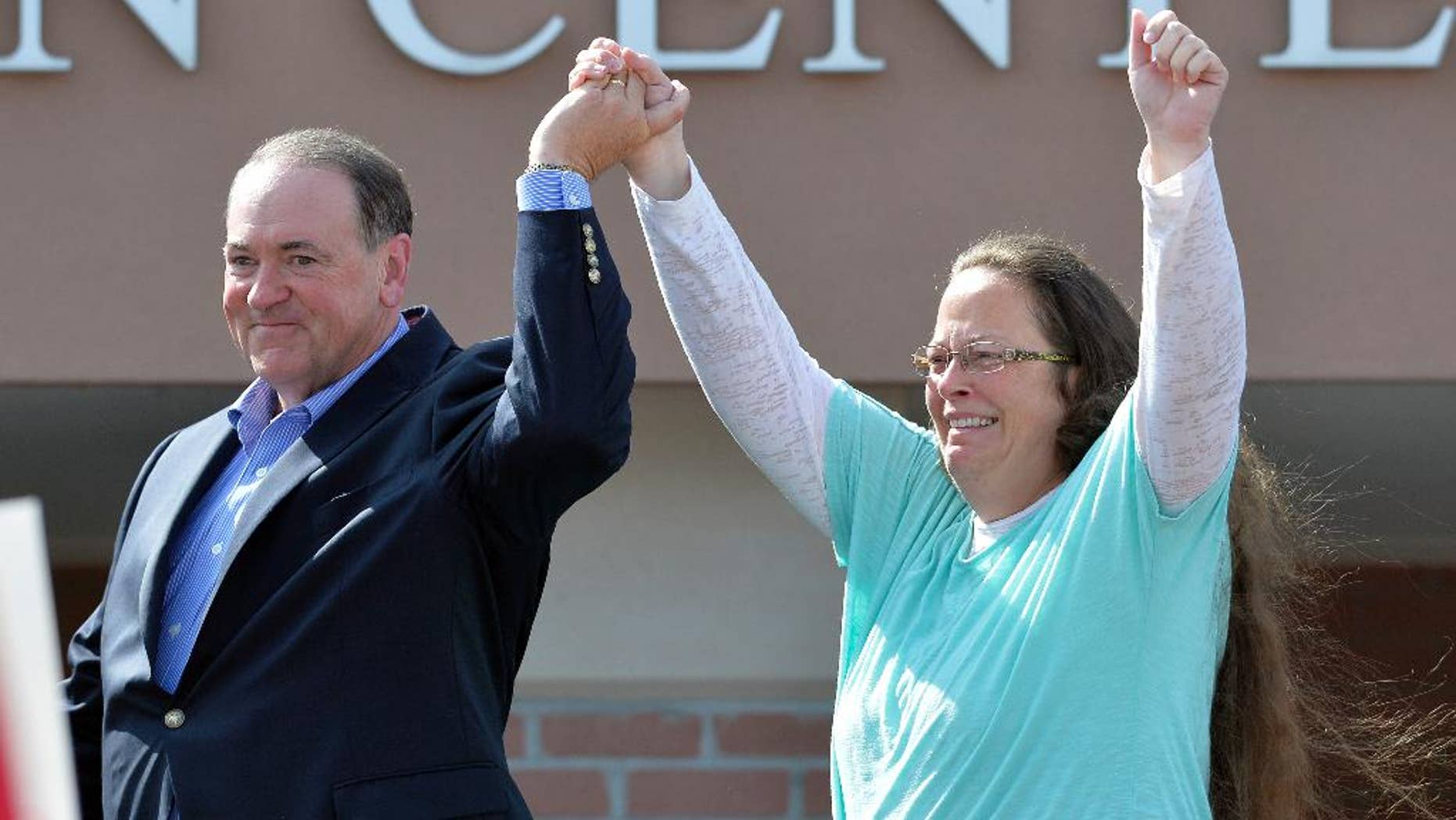 FILE - In this Tuesday, Sept. 8, 2015, file photo, Rowan County Clerk Kim Davis, with Republican presidential candidate Mike Huckabee at her side, greets the crowd after being released from the Carter County Detention Center, in Grayson, Ky. Having failed to ban same-sex marriage, many religious conservatives are now working to carve out protections for business owners and others who object to it on religious grounds. To some of them, Davis is a hero for her willingness to go to jail rather than issue marriage licenses. But others think Davis’ position as a government official makes her exactly the wrong figure to rally around. (AP Photo/Timothy D. Easley, File)