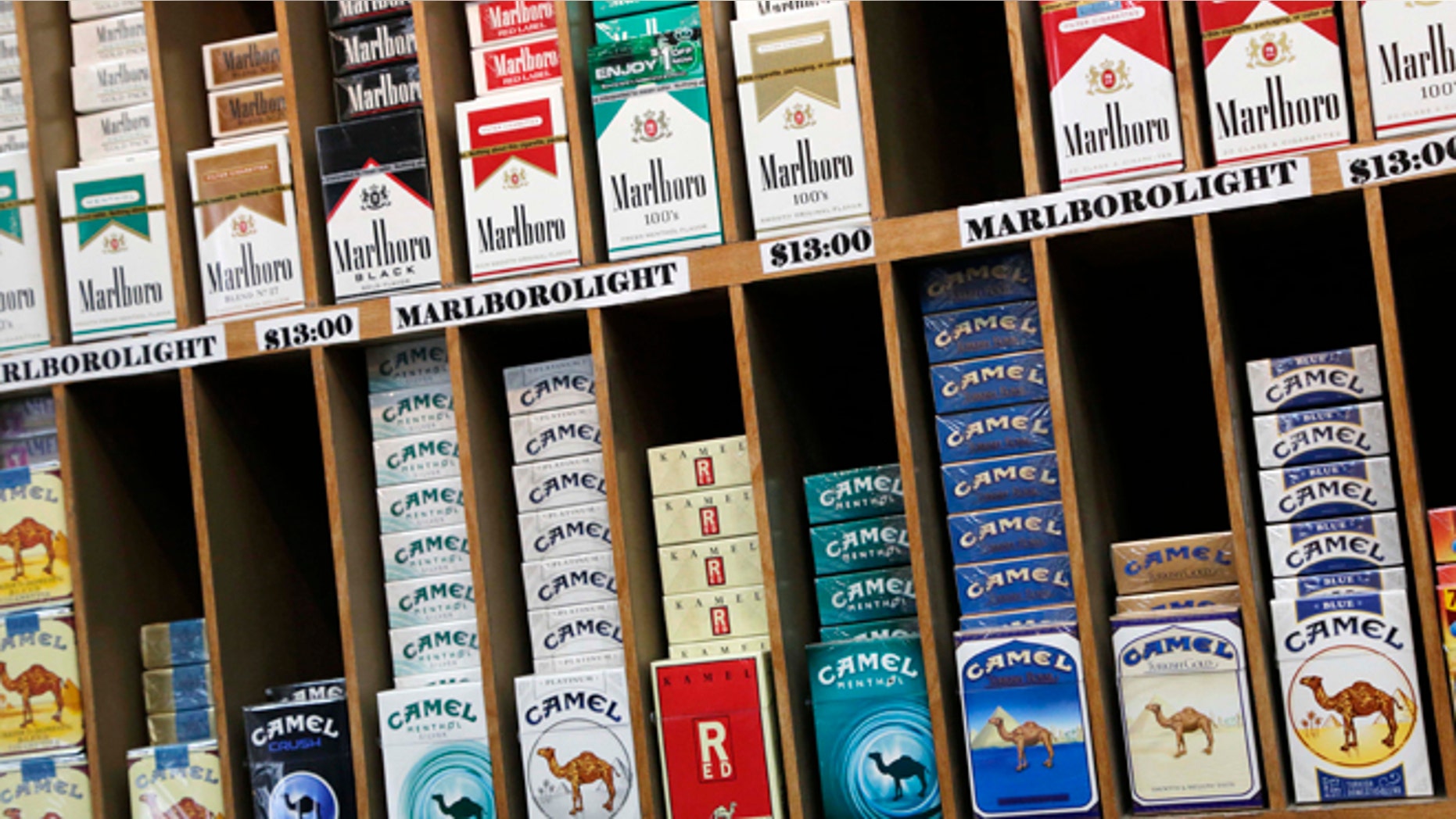 FILE- In this March 18, 2013 file photo, cigarette packs are displayed at a convenience store in New York. On Wednesday, Oct. 30, 2013, law makers in New York City voted to raise the cigarette-buying age from 18 to 21. (AP Photo/Mark Lennihan, File)