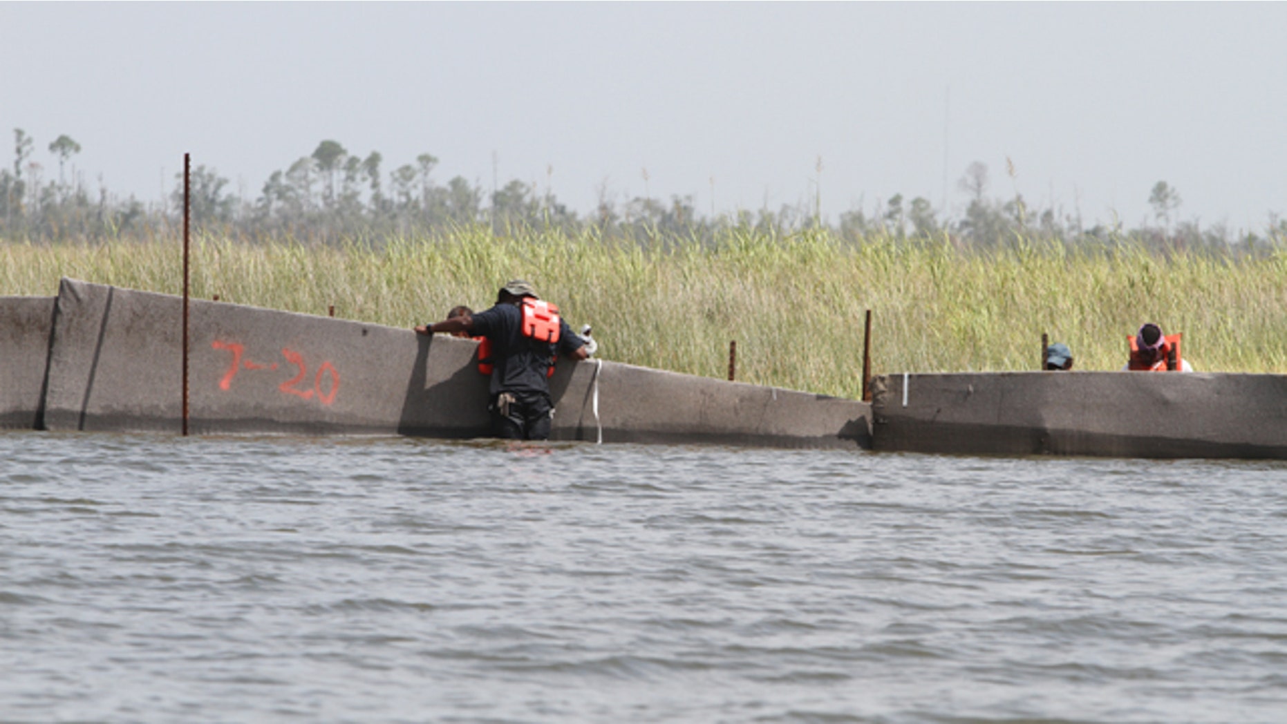 Workers double-check X-Tex fencing in the marsh along Campbell Outside Bayou near the Pearl River in Hancock County, Miss., on Friday, July 23, 2010. Put in place by contractor Environmental Protection Systems, the fencing is being used as a containment to protect Mississippi marsh areas and shorelines from the oil spill in the Gulf. Workers along the Mississippi Gulf Coast are securing oil spill protection systems ahead of the expected arrival of Tropical Storm Bonnie. (AP Photo/The Sun Herald, James Edward Bates) TV OUT; ONLINE OUT; MANDATORY CREDIT: MISSISSIPPI PRESS OUT