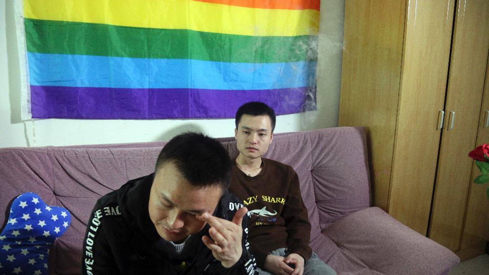 Sun Wenlin, right, sits with his partner Hu Mingliang at home.