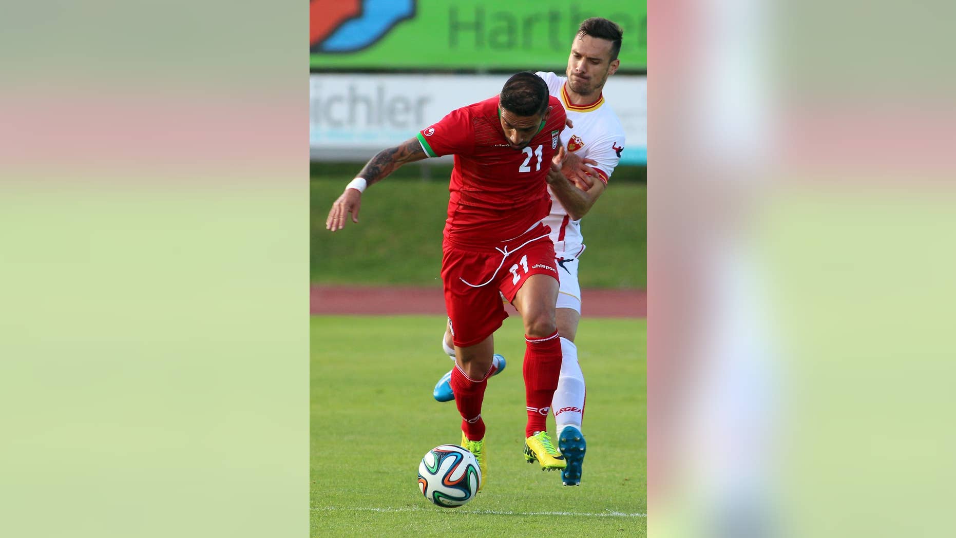 Iran's Ashkan Dejagah, left, challenges for a ball with Marko Vesovic, right, of Montenegro during a friendly soccer match between Iran and Montenegro, in Hartberg, Austria, Monday, May 26, 2014. (AP Photo/Ronald Zak)