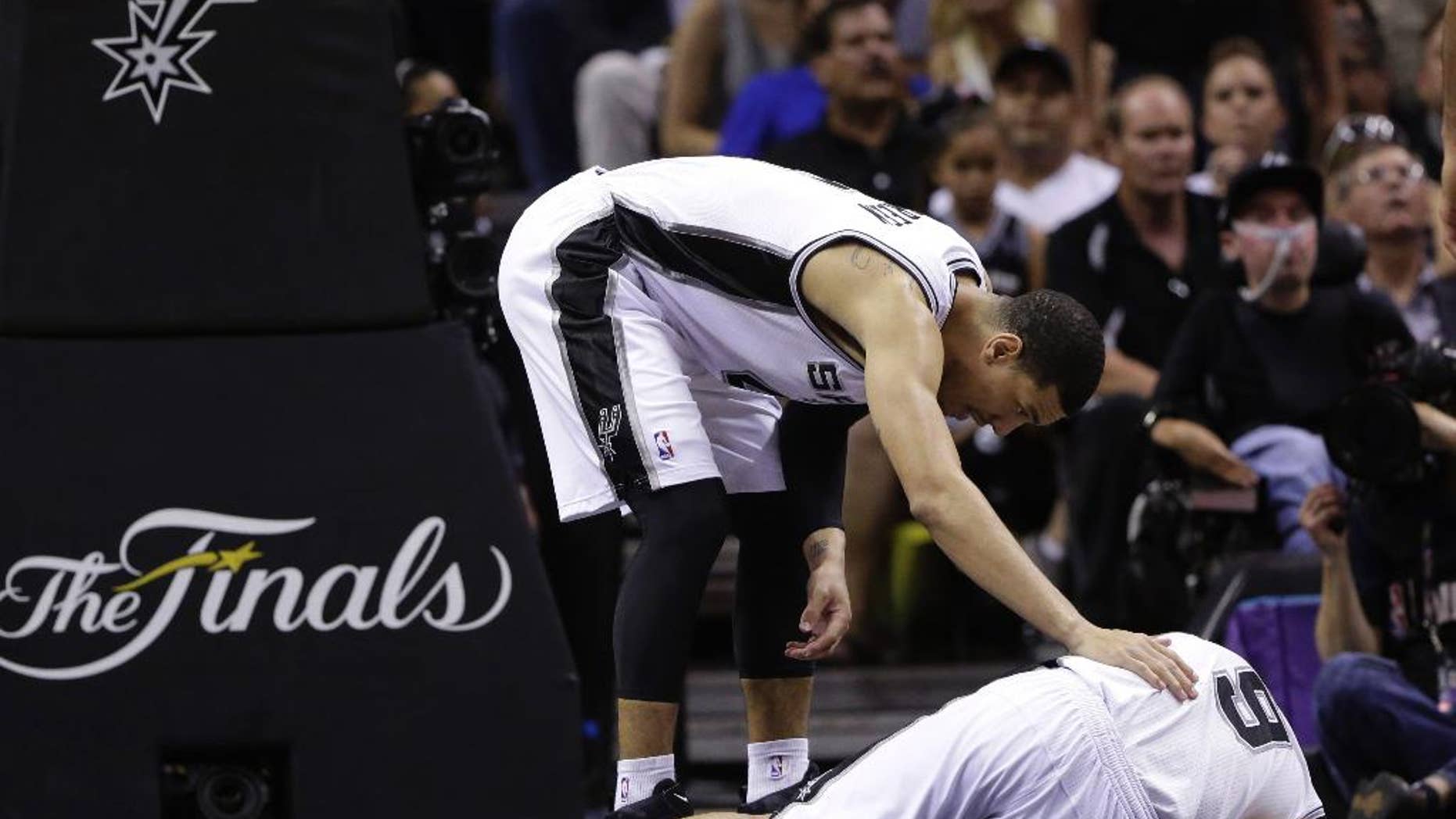San Antonio Spurs forward Tim Duncan, left, checks on guard Tony Parker during the second half in Game 2 of the NBA basketball finals against the Miami Heat on Sunday, June 8, 2014, in San Antonio. Miami won 98-96. (AP Photo/Eric Gay)