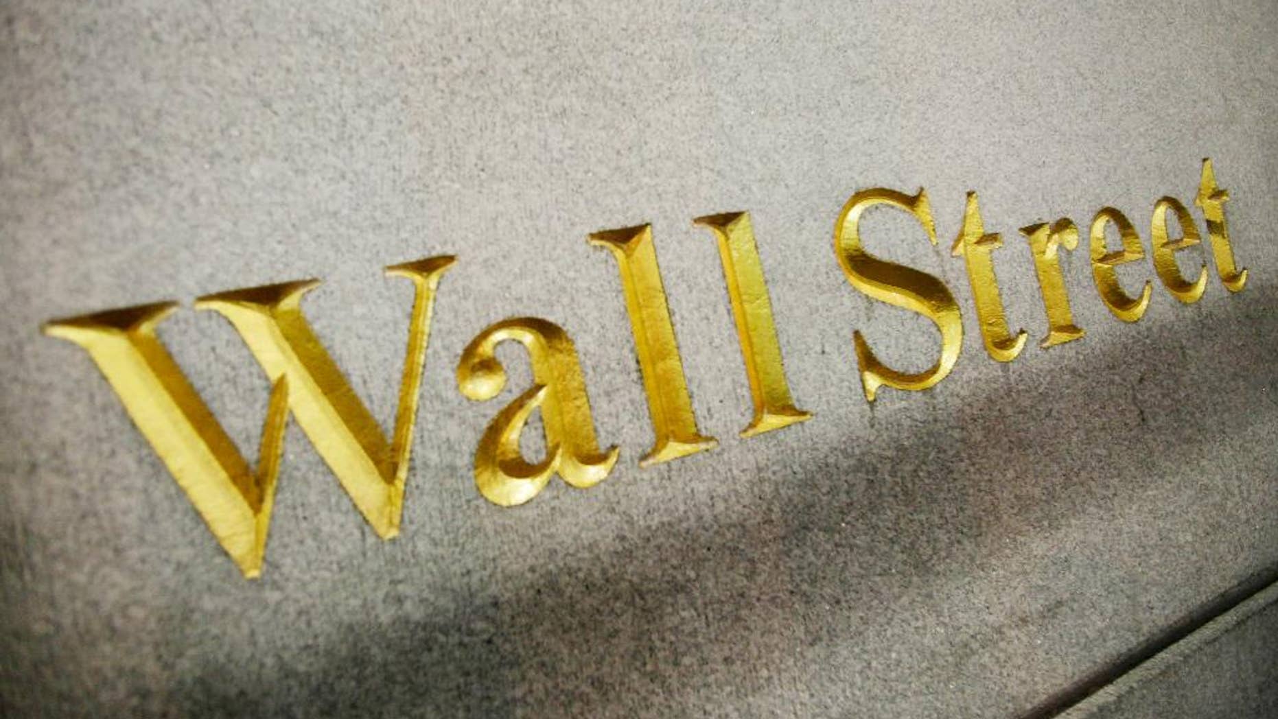 FILE - This Oct. 8. 2014, file photo, shows a Wall Street address carved into the side of a building in New York. U.S. stocks are opening the year on a strong note, but energy stocks slipped as the price of crude oil resumed its slide, Friday, Jan. 2, 2015. (AP Photo/Mark Lennihan, File)